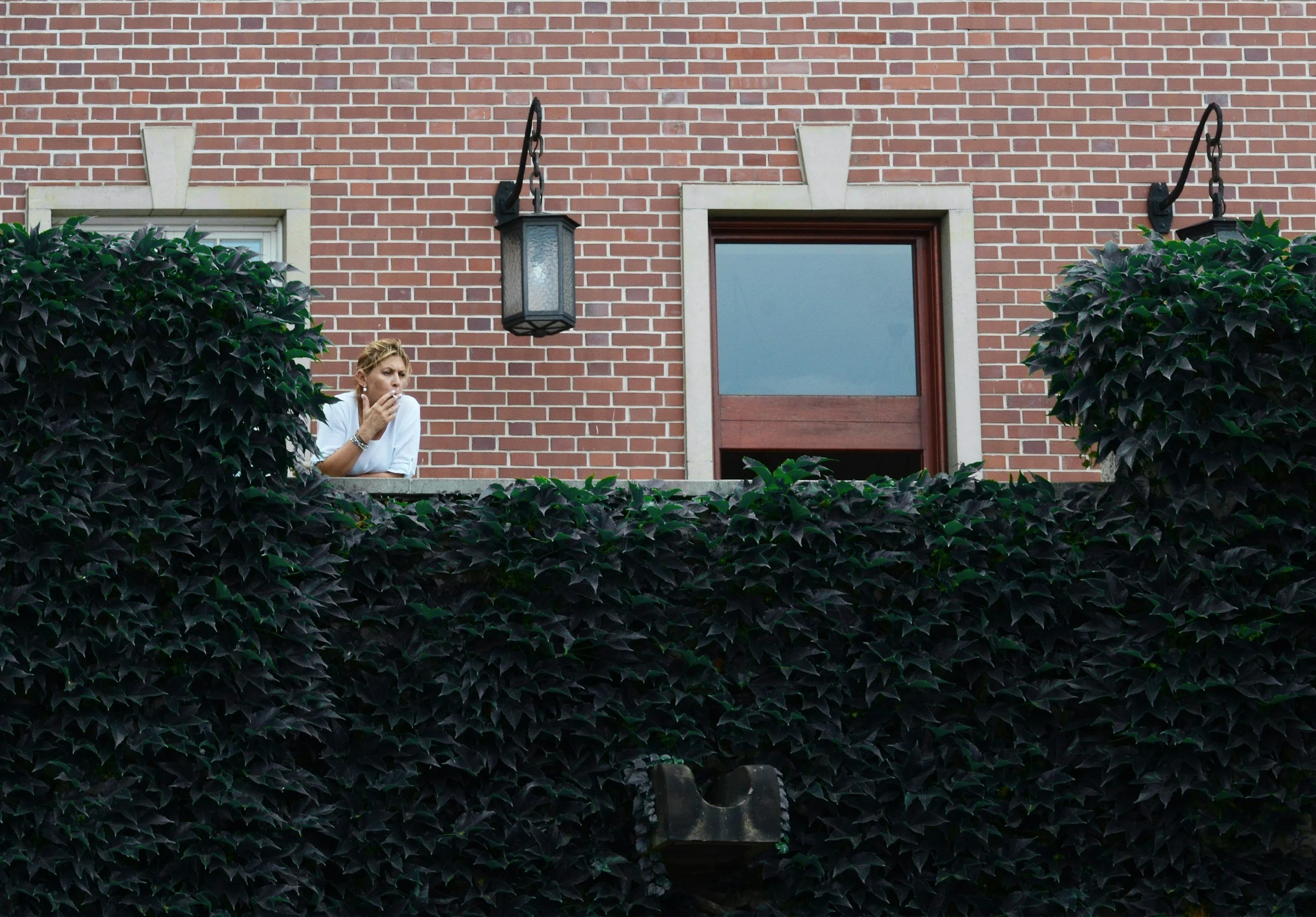 Woman taking a solo smoke break by a brick building, illustrating why stop smoking methods fail to address the grief.