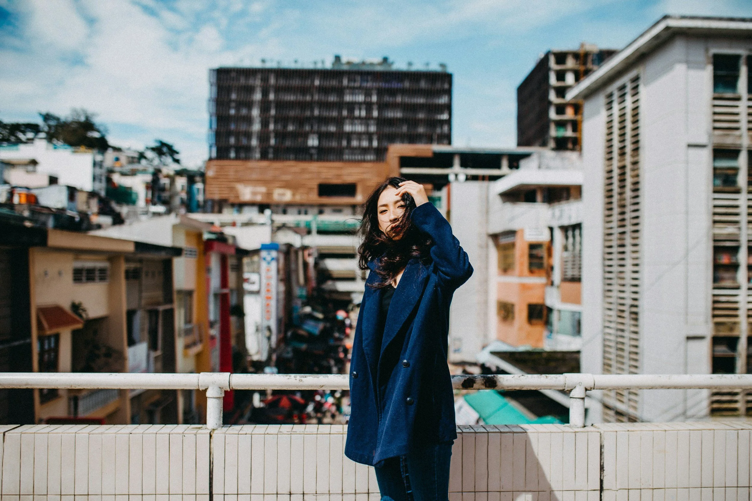 Young woman in navy coat standing calm above a city, illustrating how to stop smoking easily in a busy life
