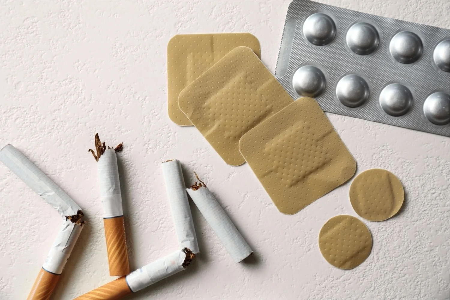 A pile of nicotine patches, stop smoking medication and broken cigarettes on a light surface illustrating the products women have tried to quit smoking