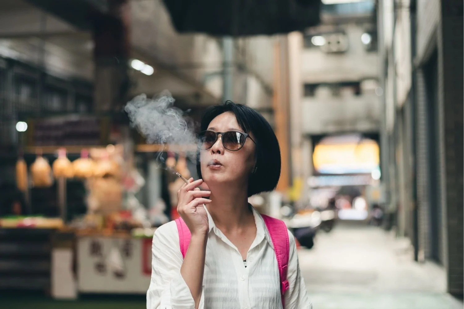 Woman in sunglasses smoking a cigarette on a busy city street illustrating the hidden fears women carry about who they'll be when they stop smoking