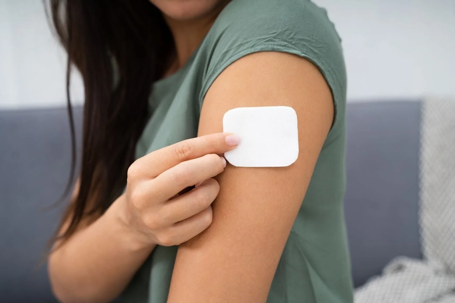 Woman placing a nicotine patch on her upper arm illustrating why patches don't work for women trying to quit smoking