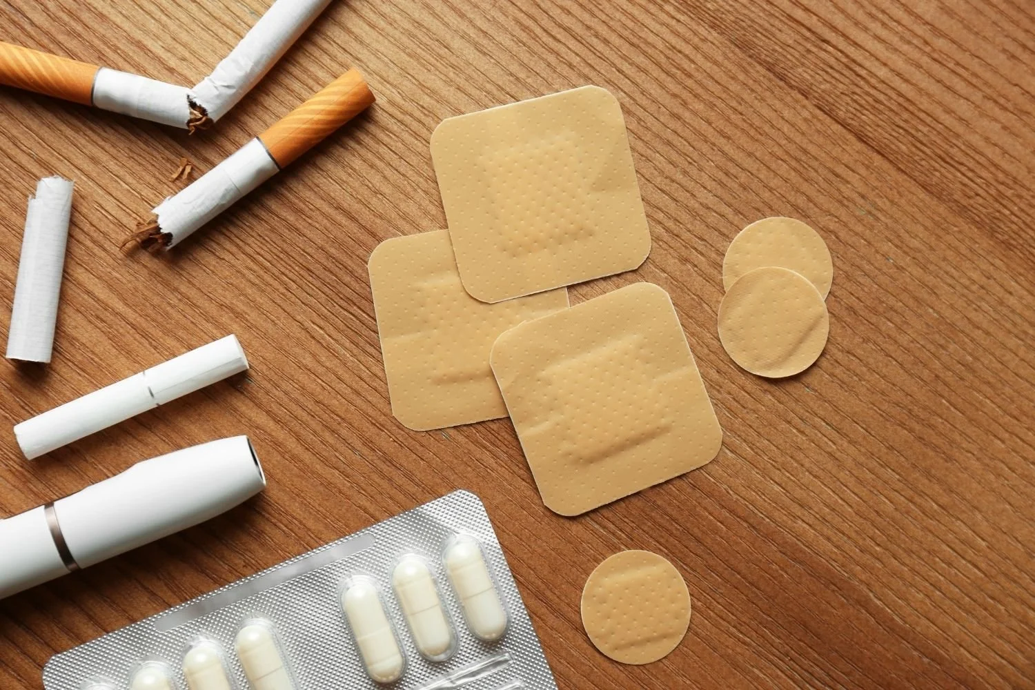 Flat-lay of nicotine patches, gum, vape and stop-smoking medication illustrating why nicotine replacement doesn't work for women trying to stop smoking.