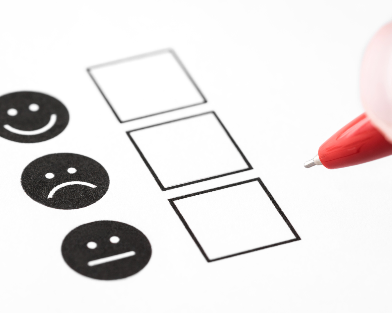 Form with a smiling face, sad face, and neutral face. A red pen hovers over it.