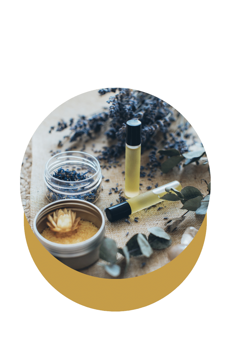 Vials de parfum ou huiles essentielles, pot de plantes séchées et éléments végétaux sur une surface en tissu beige.
