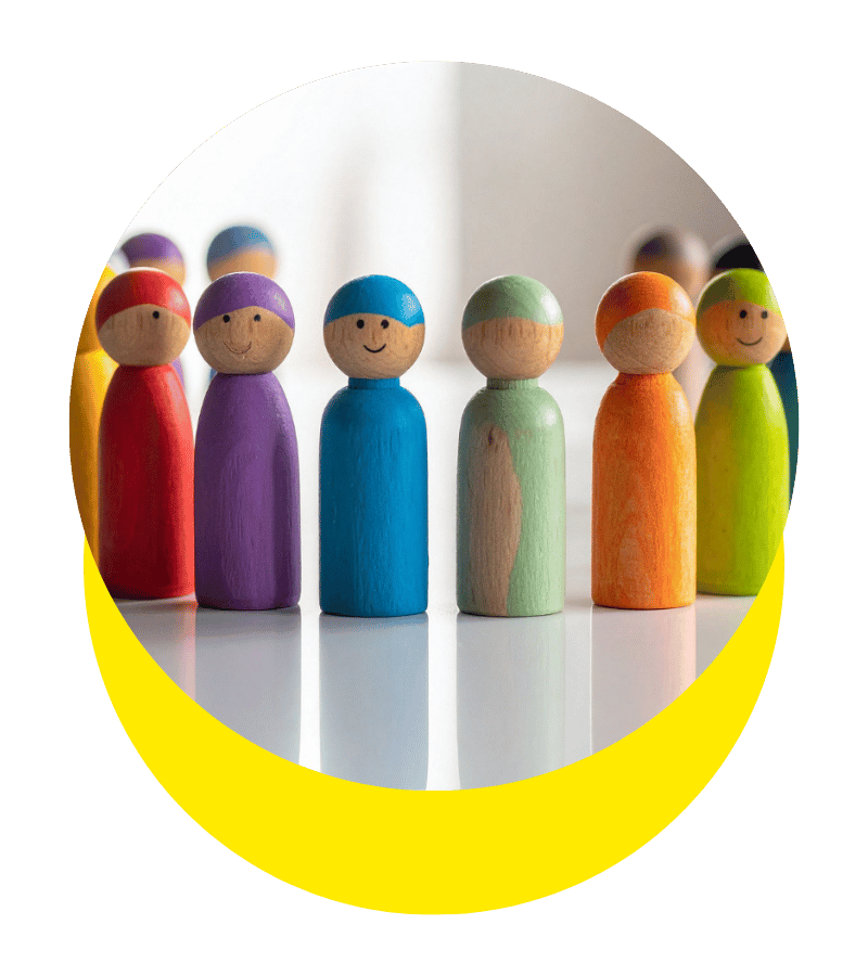 Groupe de figurines en bois peintes de différentes couleurs, représentant des personnes, alignées en rangée.