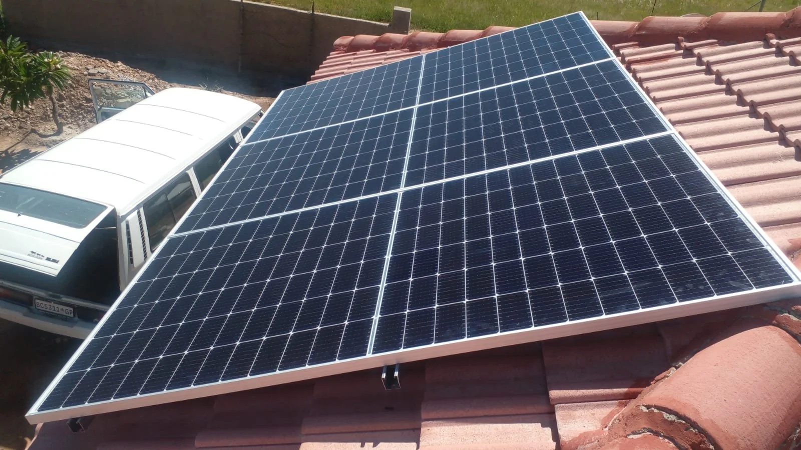Solar panels installed on a rooftop next to a white van.