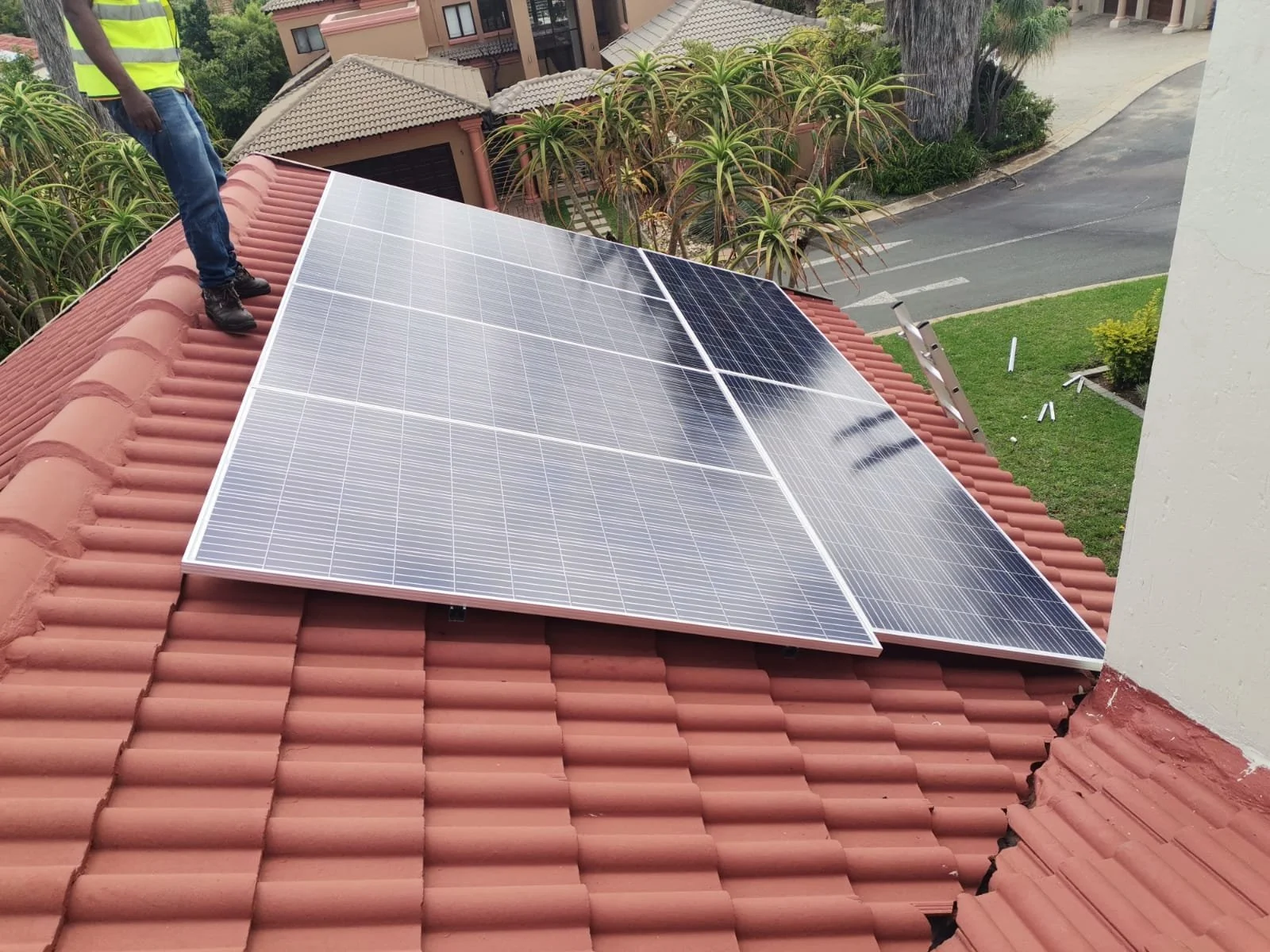 Solar panels installed on a red tiled roof, with a person standing on the roof near the panels.