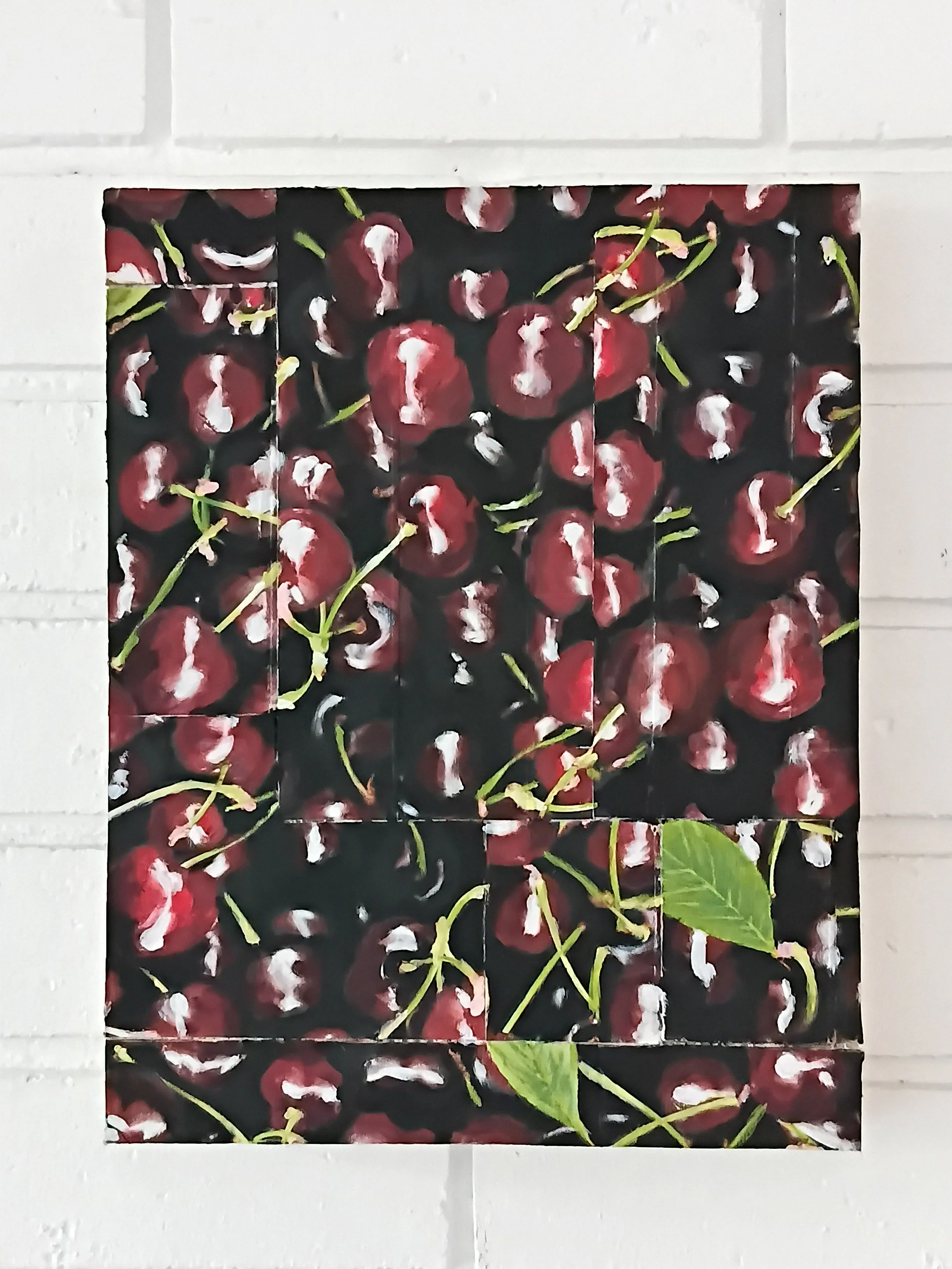 Detached painting or photograph of cherries with green leaves on a dark background, mounted on a white brick wall.