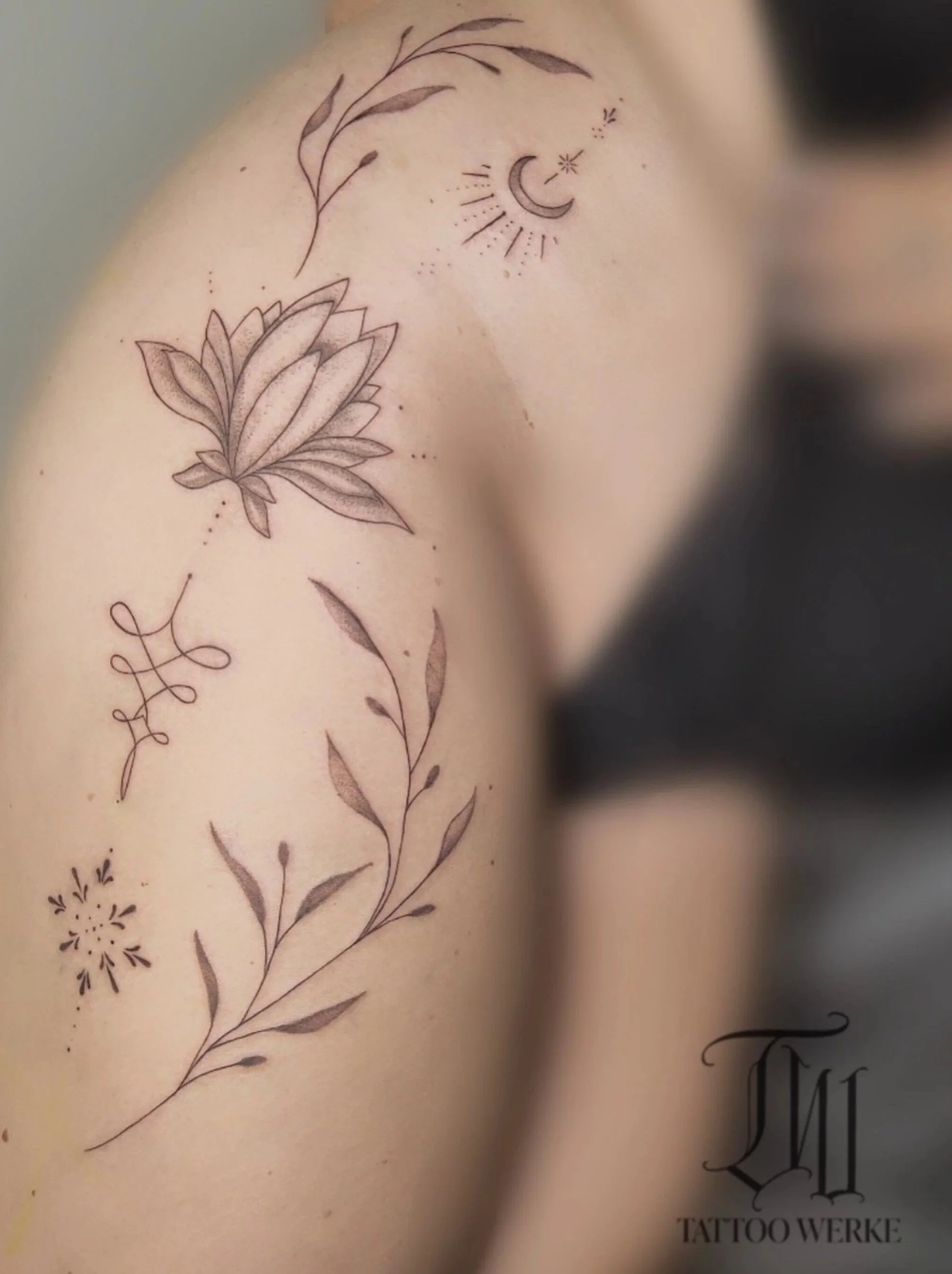 Tattoo mit Blumenmuster und einem Halbmond mit Sonnenstrahlen umgeben, auf einer menschlichen Haut