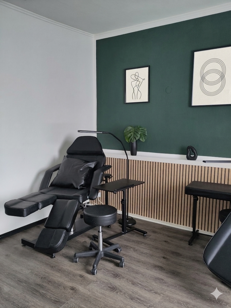 Behandlungsraum mit schwarhem Liegestuhl, Stuhl, Wanddekorationen, Pflanze, Tisch und Holzpaneelen an der Wand