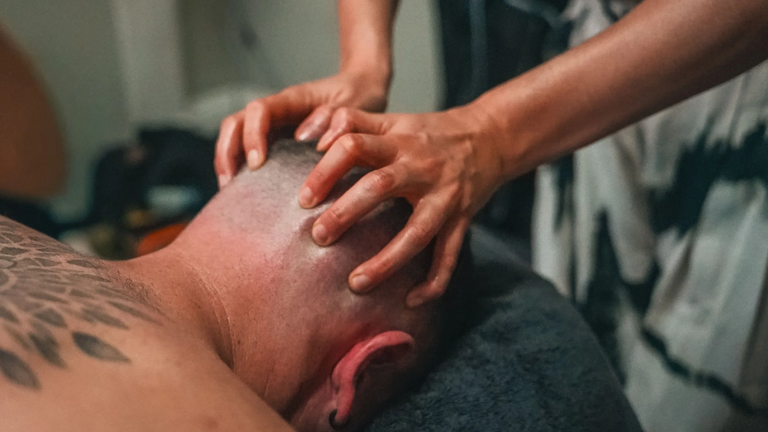 Person receiving a massage on their shoulder with hands pressing on the skin.