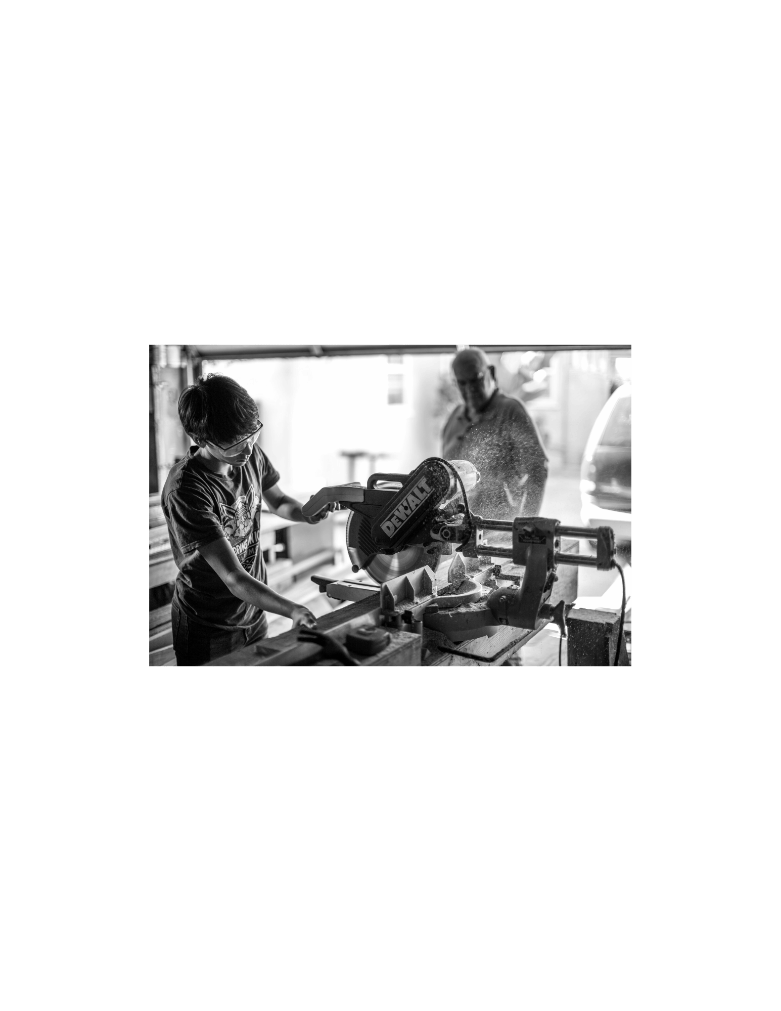 a younger tradesperson being supervised by an older tradesperson while using a chop saw