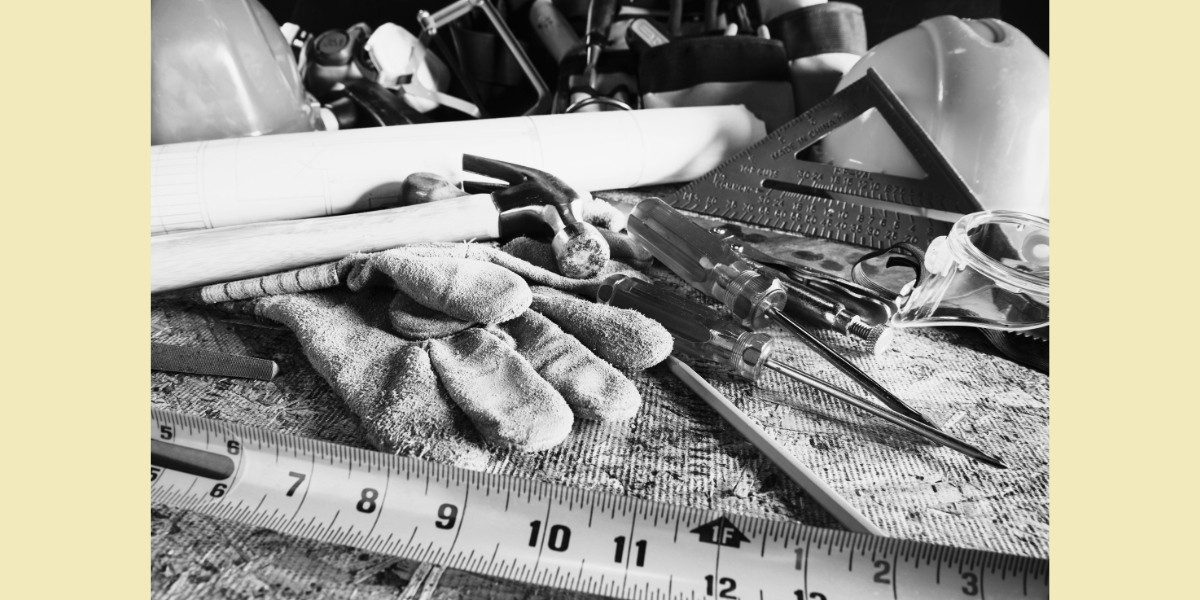 A workbench with a tape measurer, gloves and a hammer
