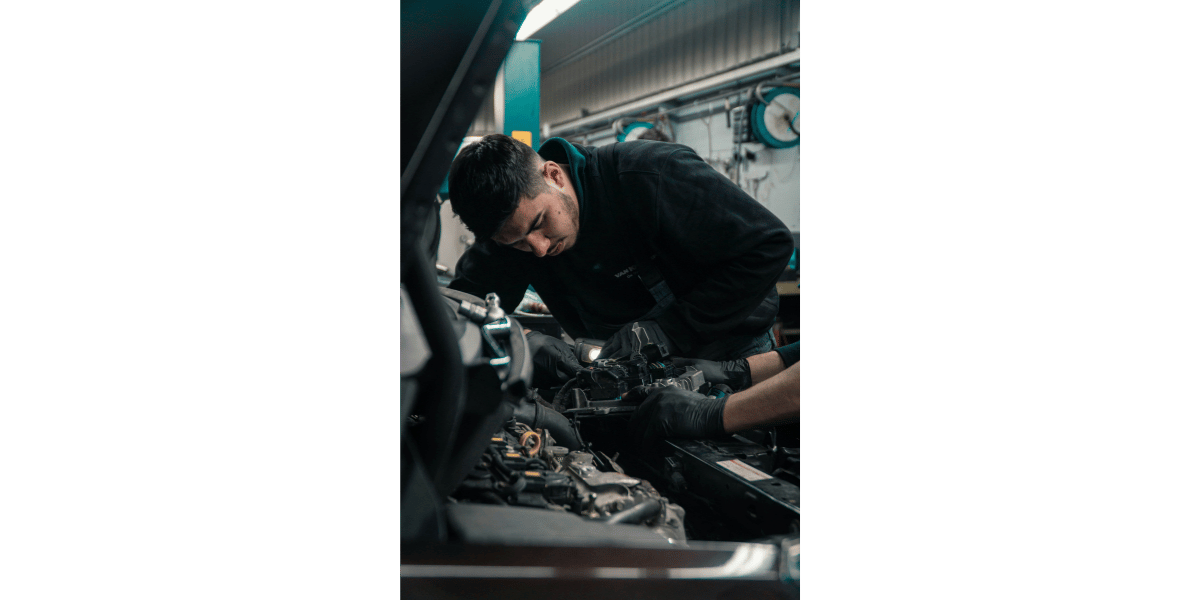 A CTE shop class student with some tools working on a car.