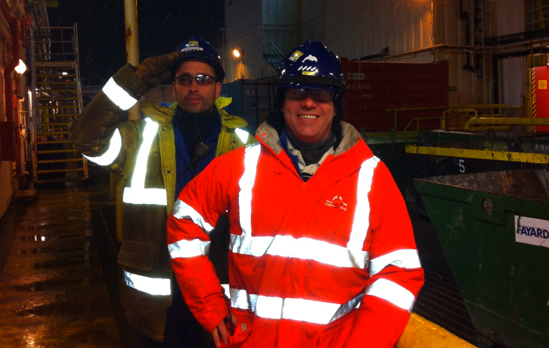 Two workers in safety gear and helmets on an industrial site at night.