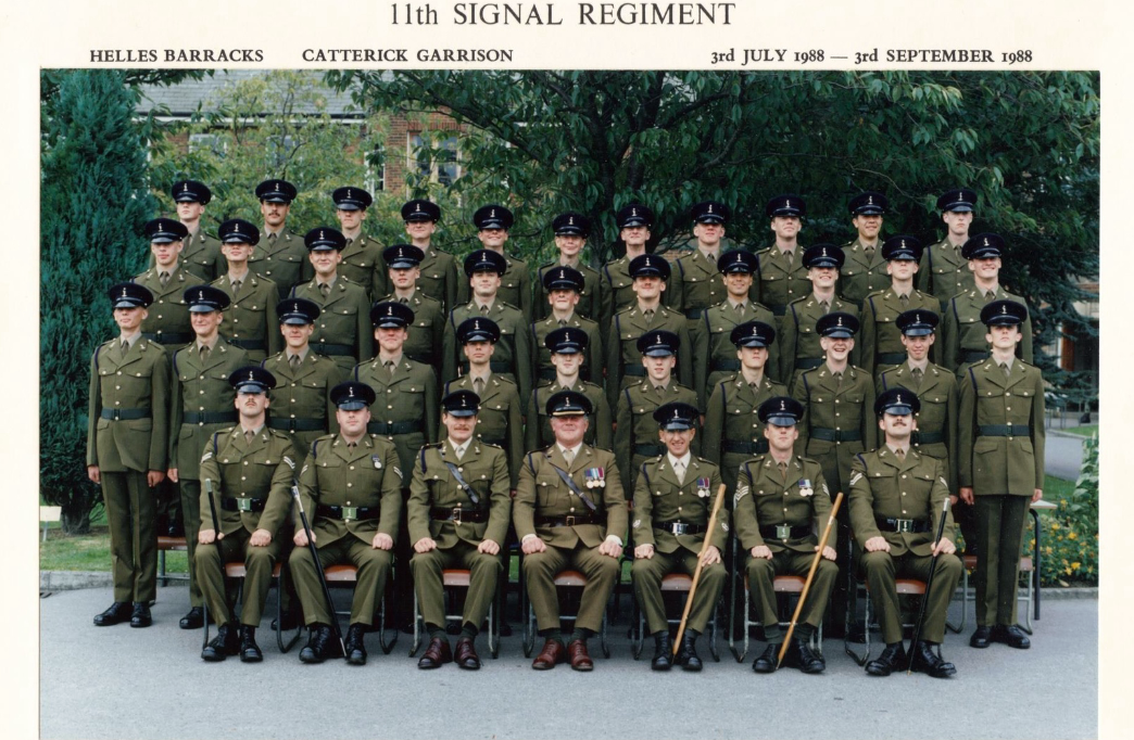 Group photo of military personnel in uniform, assembled outdoors in front of trees. The photo is labeled '11th Signal Regiment' with locations and dates 'Helles Barracks, Catterick Garrison, 3rd July 1988 – 3rd September 1988' at the top.
