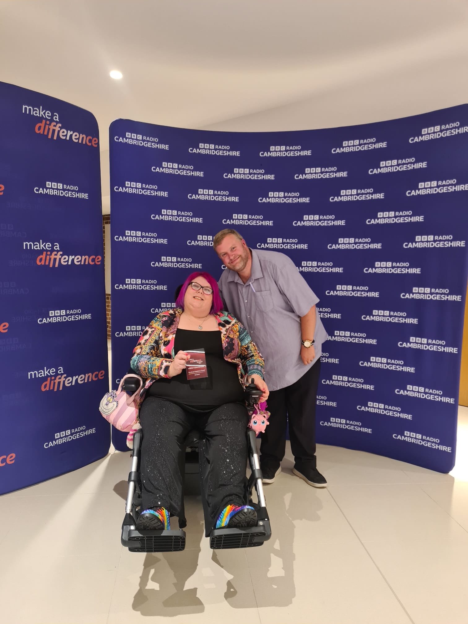 Sitting in my wheelchair holding my finalist award with my husband next to me