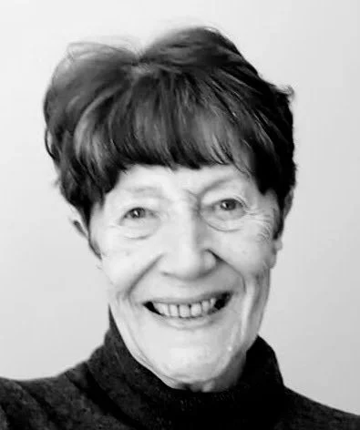 Black and white portrait of an elderly woman with short, wavy hair smiling at the camera.