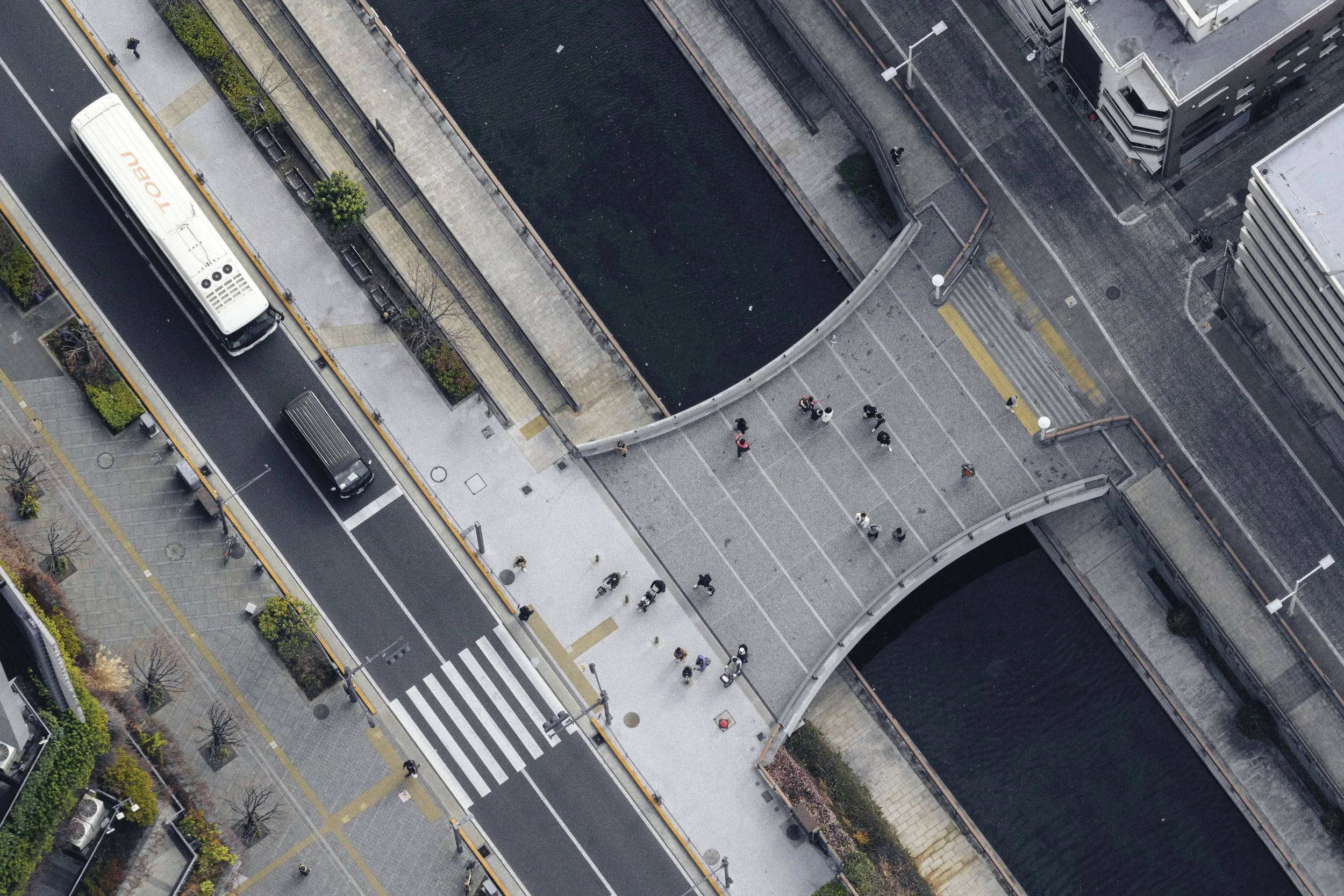 Aerial view of a city street with a bike lane, a bus, pedestrians, and surrounding buildings.