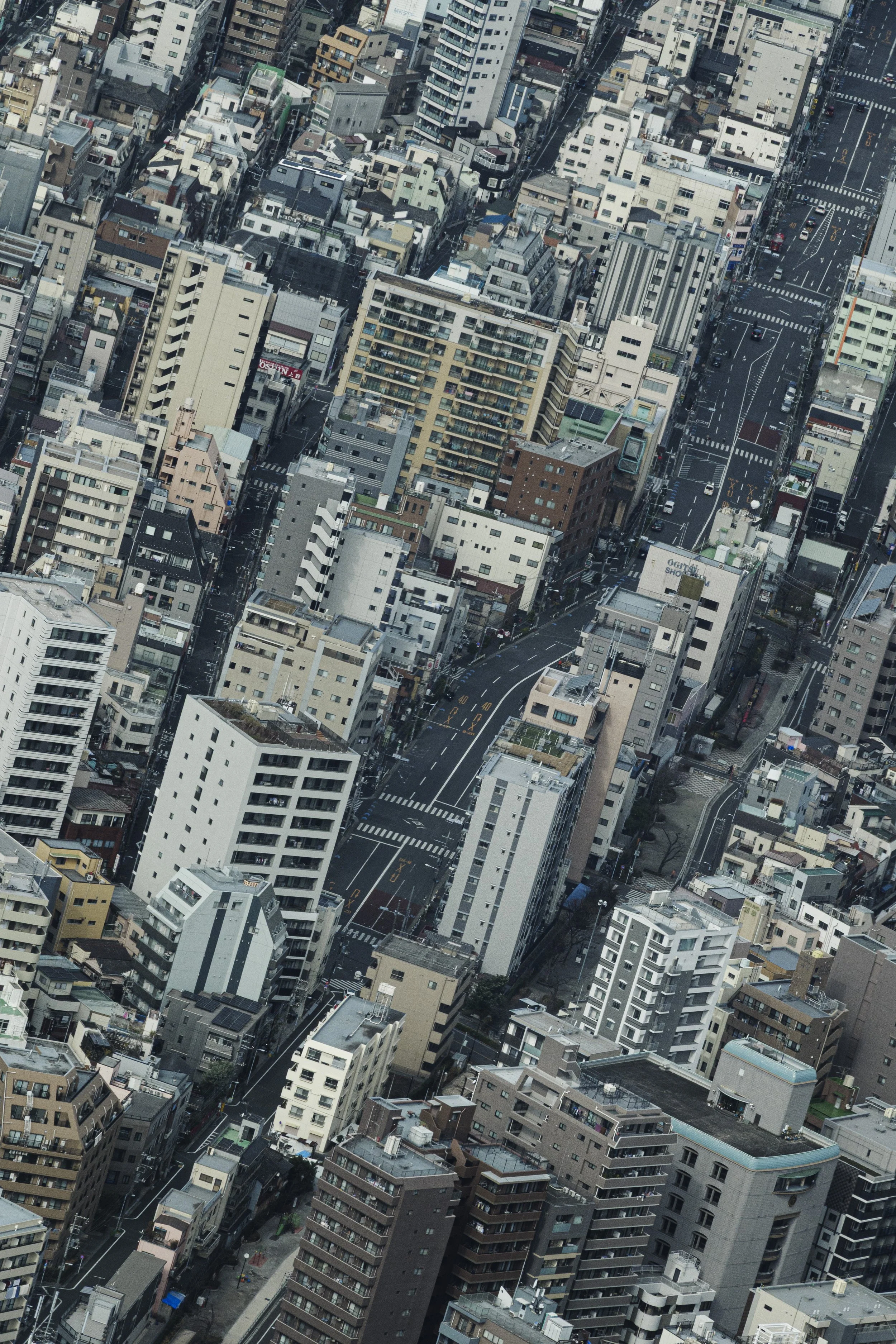 Aerial view of a dense cityscape with high-rise buildings, streets, and cars in an urban area.