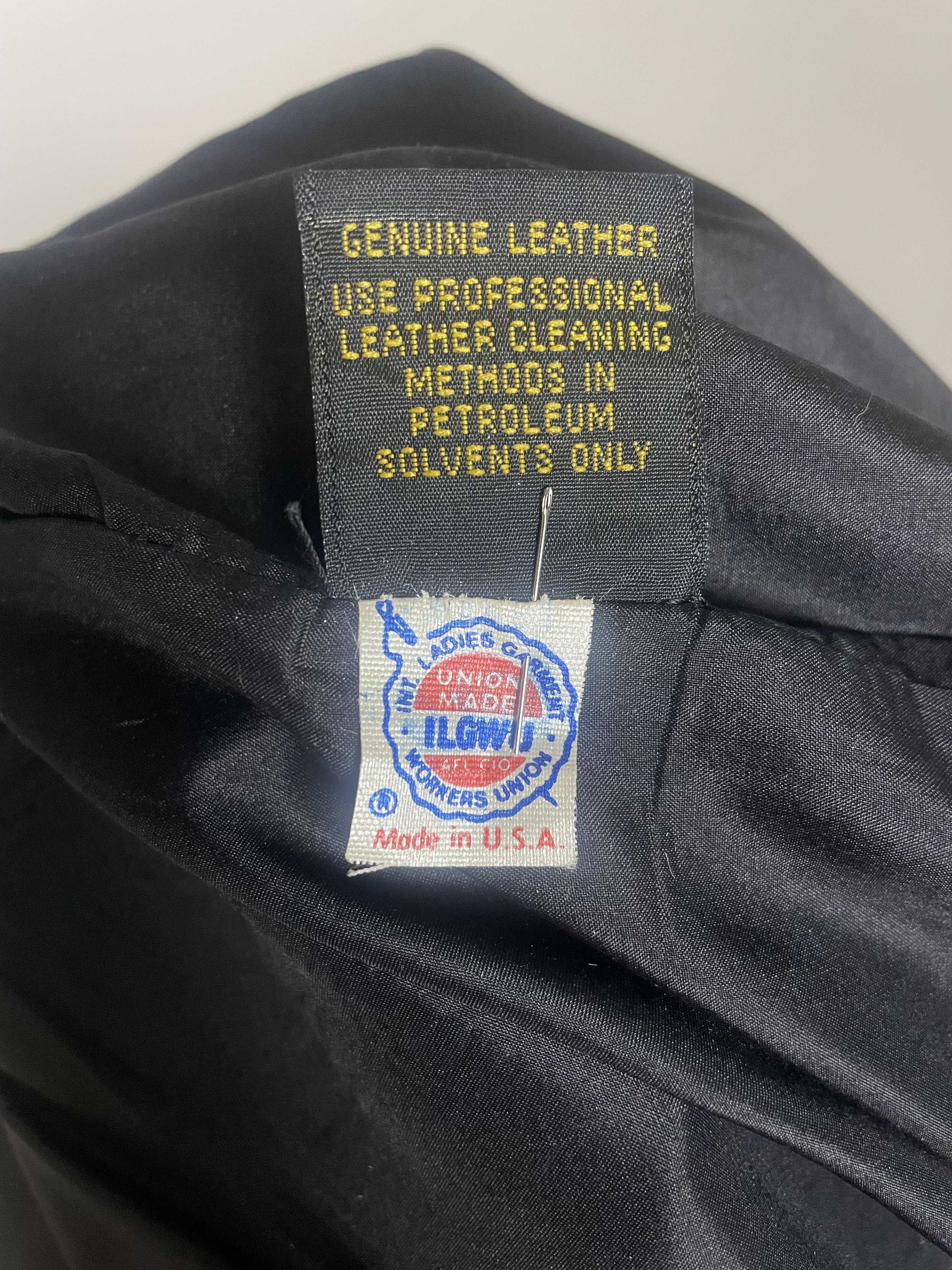 Close‑up of the genuine leather material tag and ILGWU union label showing fiber content and era‑specific construction.