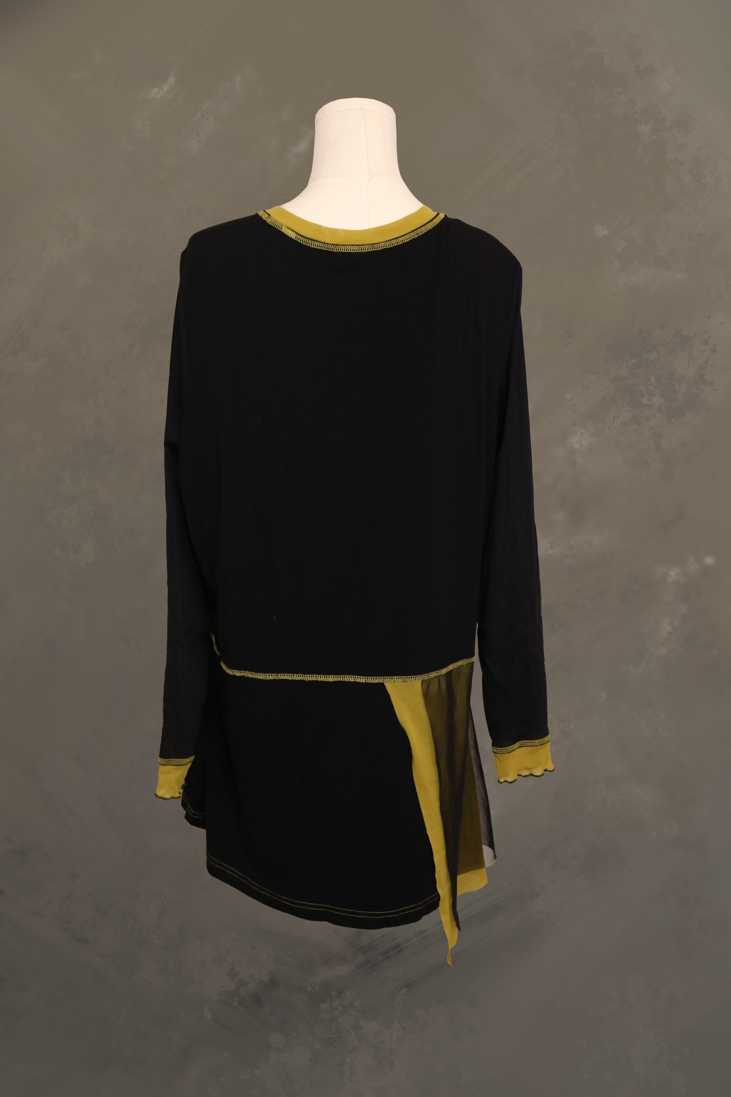 back view of the black fred sabatier tunic on a dress form. features an asymmetrical olive green mesh overlay extending down the lower panel, clean black shoulder lines, and contrast stitch detailing.
