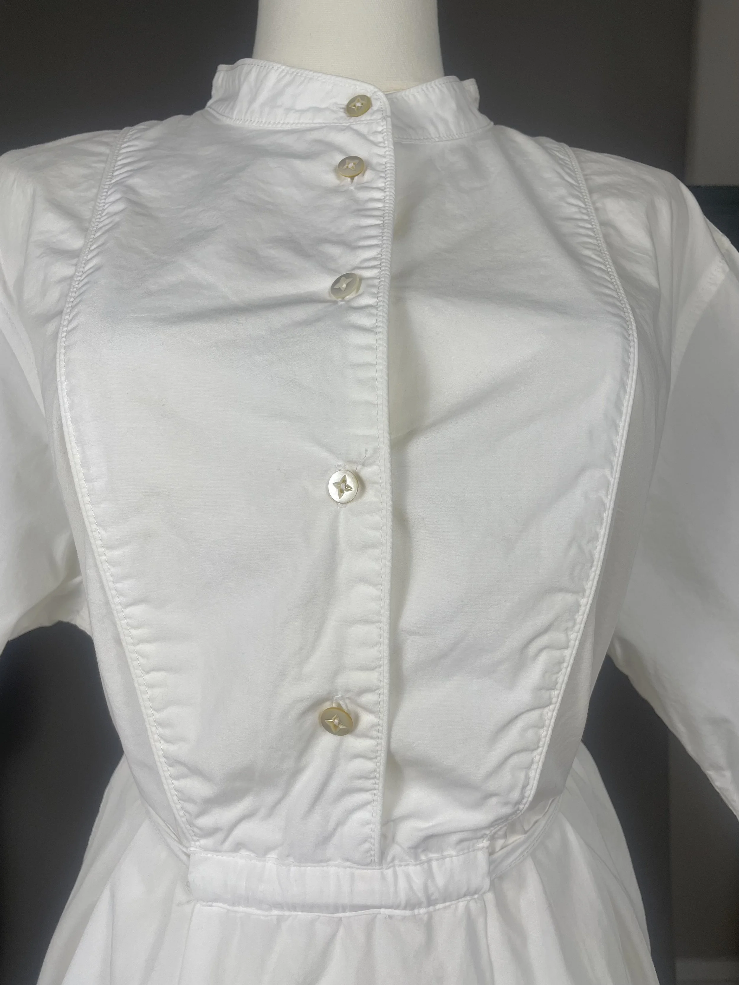 Close‑up of the front button showing the clean cotton placket and minimal construction.