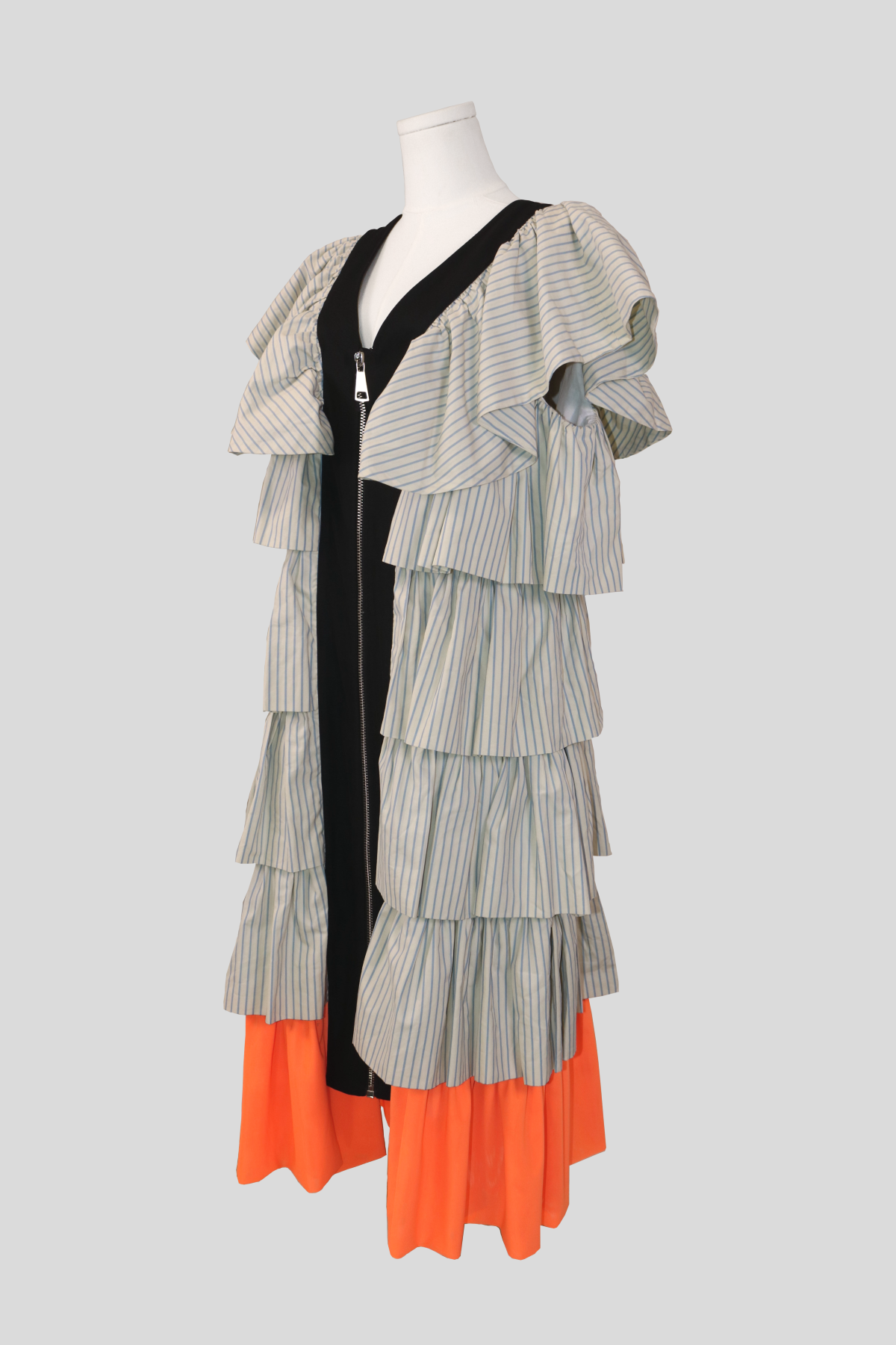 profile view of the joanne hynes pinstripe frill dress. highlights the sculptural dimension and high volume of the tiered ruffles extending outward from the armholes down to the contrasting orange lower trim.