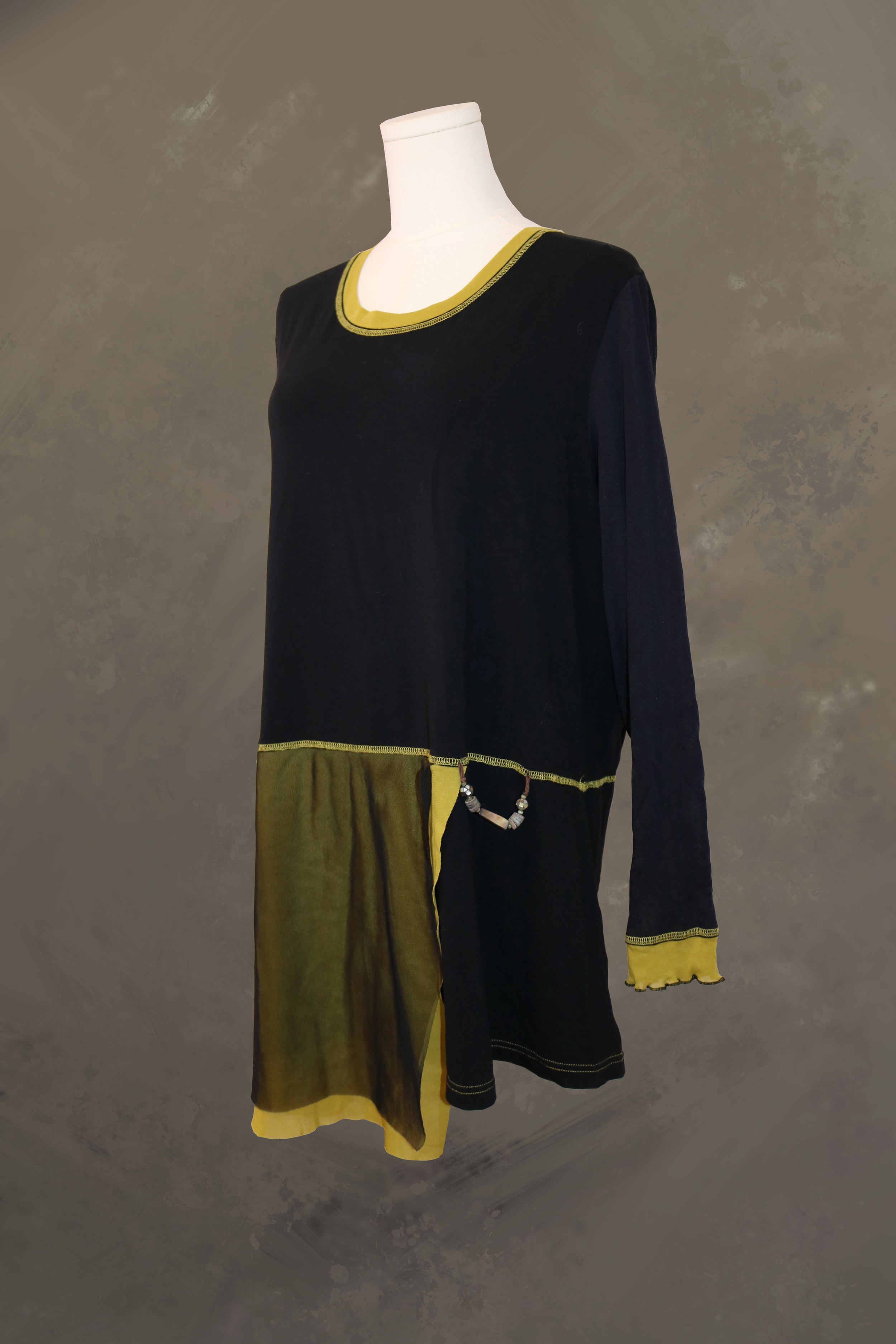 profile view of the black fred sabatier asymmetrical tunic. highlights the layered drape of the sheer olive green mesh panels along the hem and the elongated, structured line of the long black sleeves.