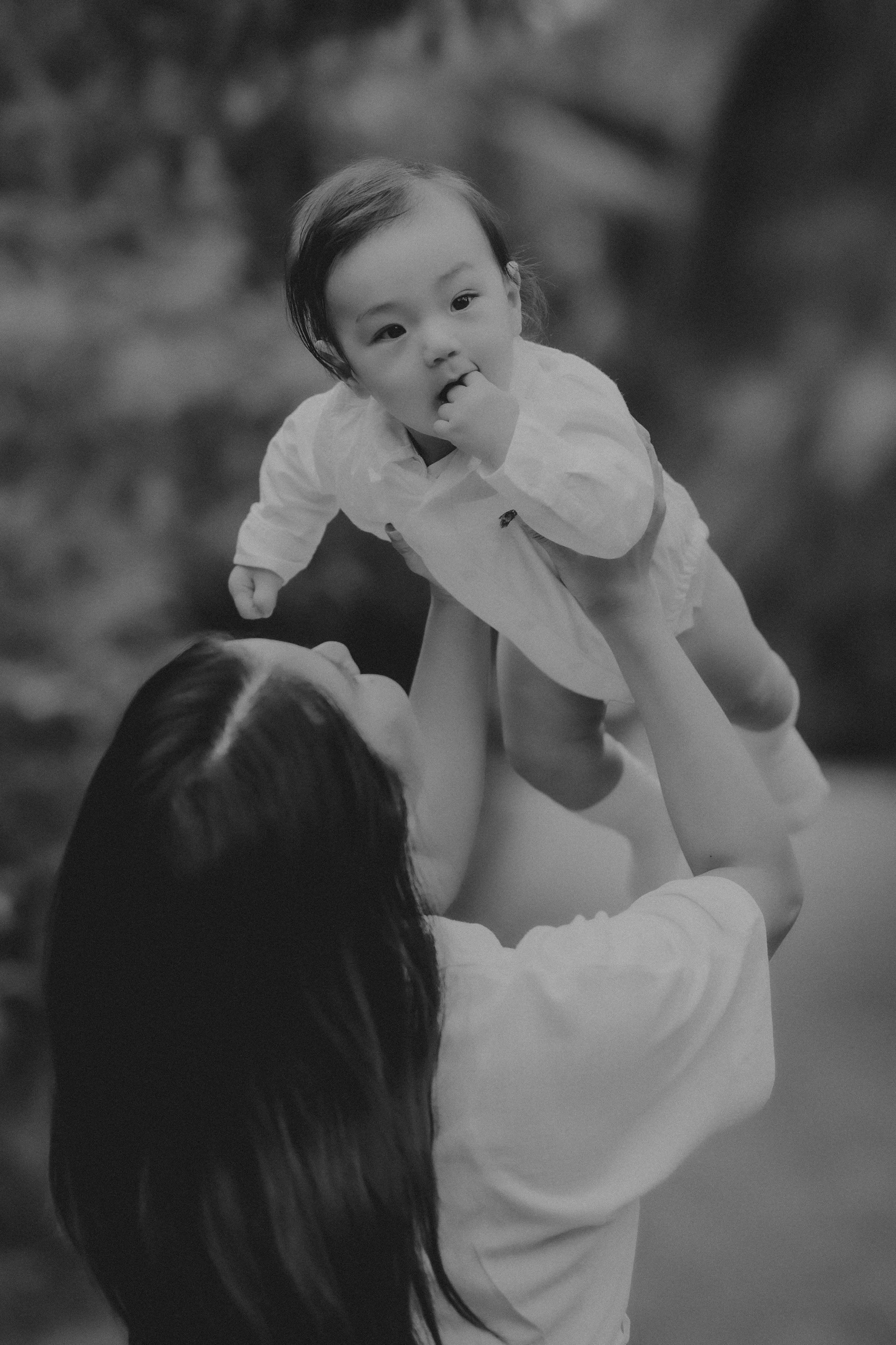Daytime postpartum doula Jamee Leann Vasquez holds a baby in the air outside in Santa Clara.