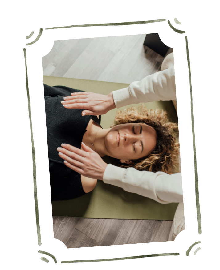 A full spectrum doula holds their hands over a postpartum mother during a reiki session in Santa Clara, California.