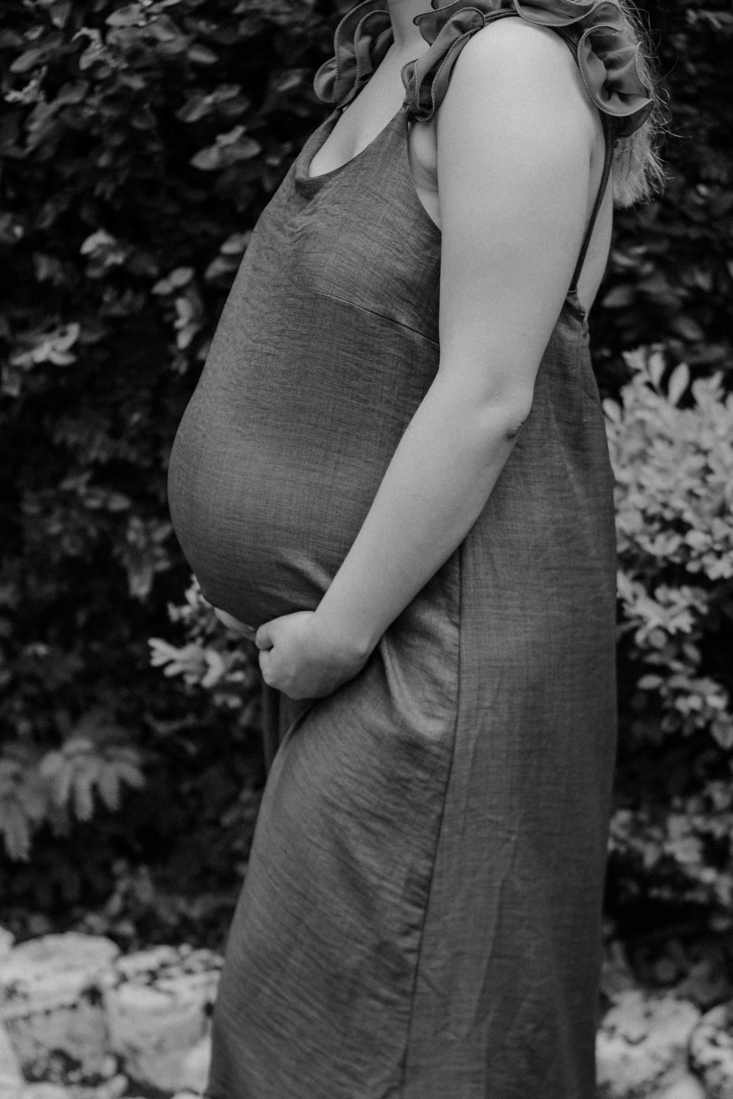 A pregnant woman in Santa Clara, who is working with Flourish & Flow's birth doula, holds her stomach outside.