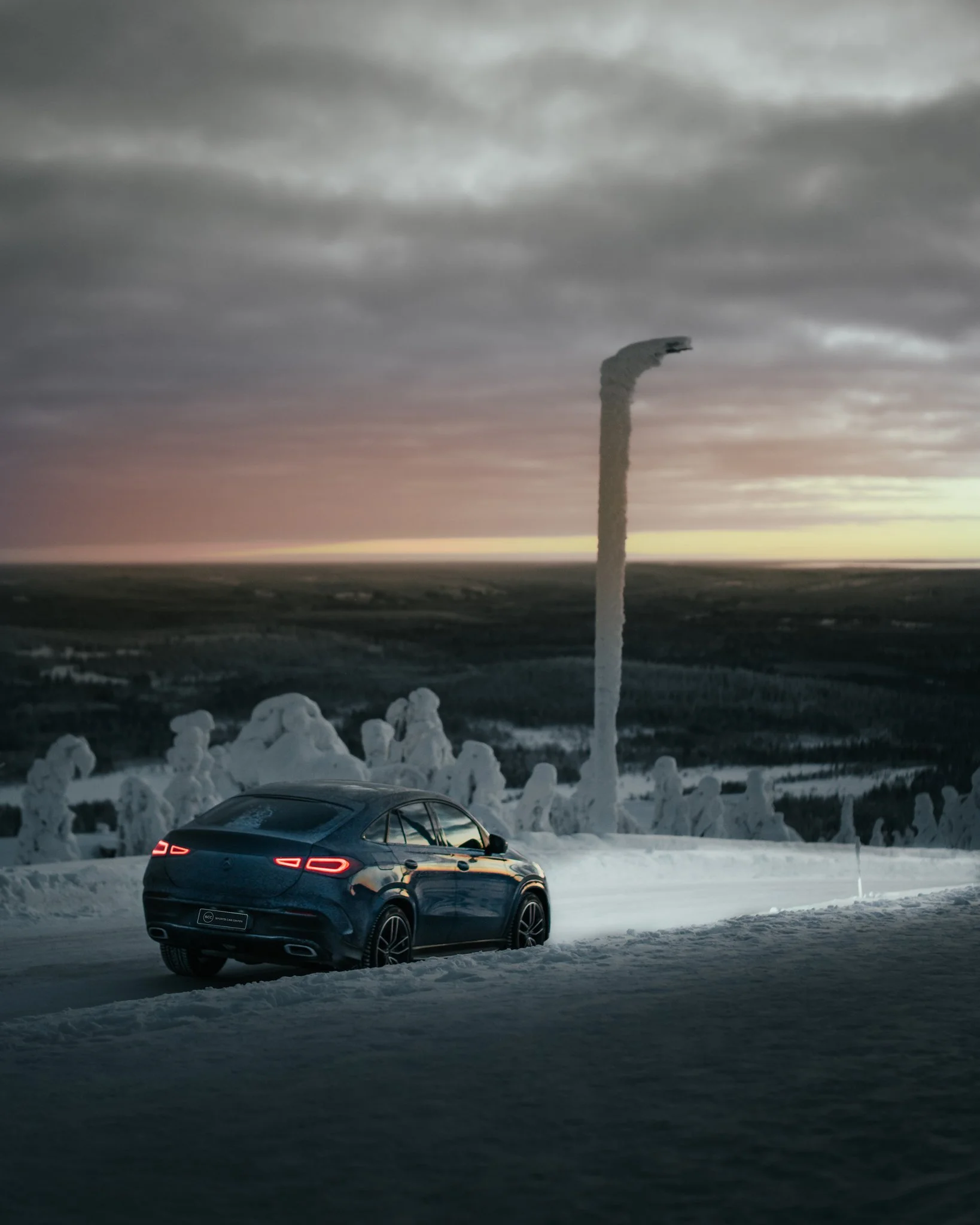 BMW m8 ajamassa lumisella tiellä talvimaisemassa, taivaalla pilviä auringonlaskun aikaan.