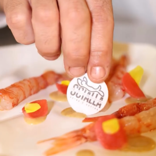 Una mano che tiene una cialda alimentare con il logo che identifica il nome del ristorante che ha realizzato un fantastico piatto nel suo ristorante