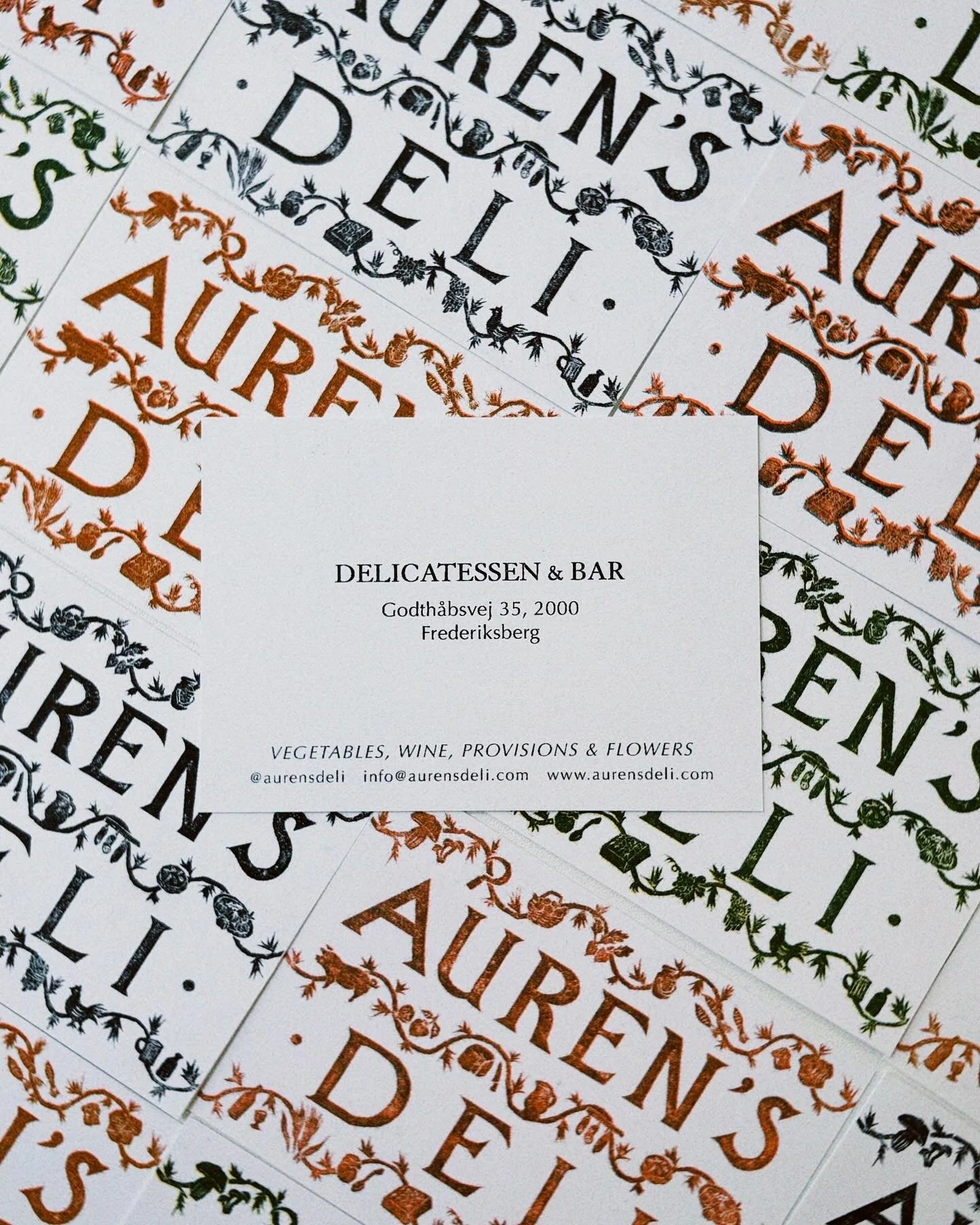 Business cards for a delicatessen and bar, including contact information and address, with decorative borders in black and copper