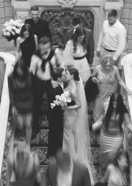 Couple kissing at a wedding ceremony with guests gathered around them.