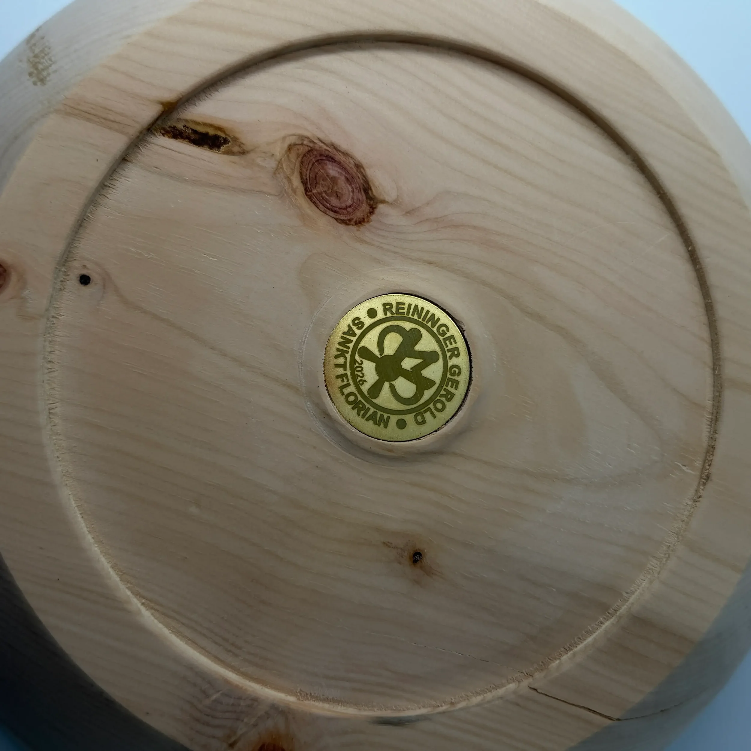Detail Unterseite: Holzmaserung und Markenplakette an der Zirbenholz-Schale