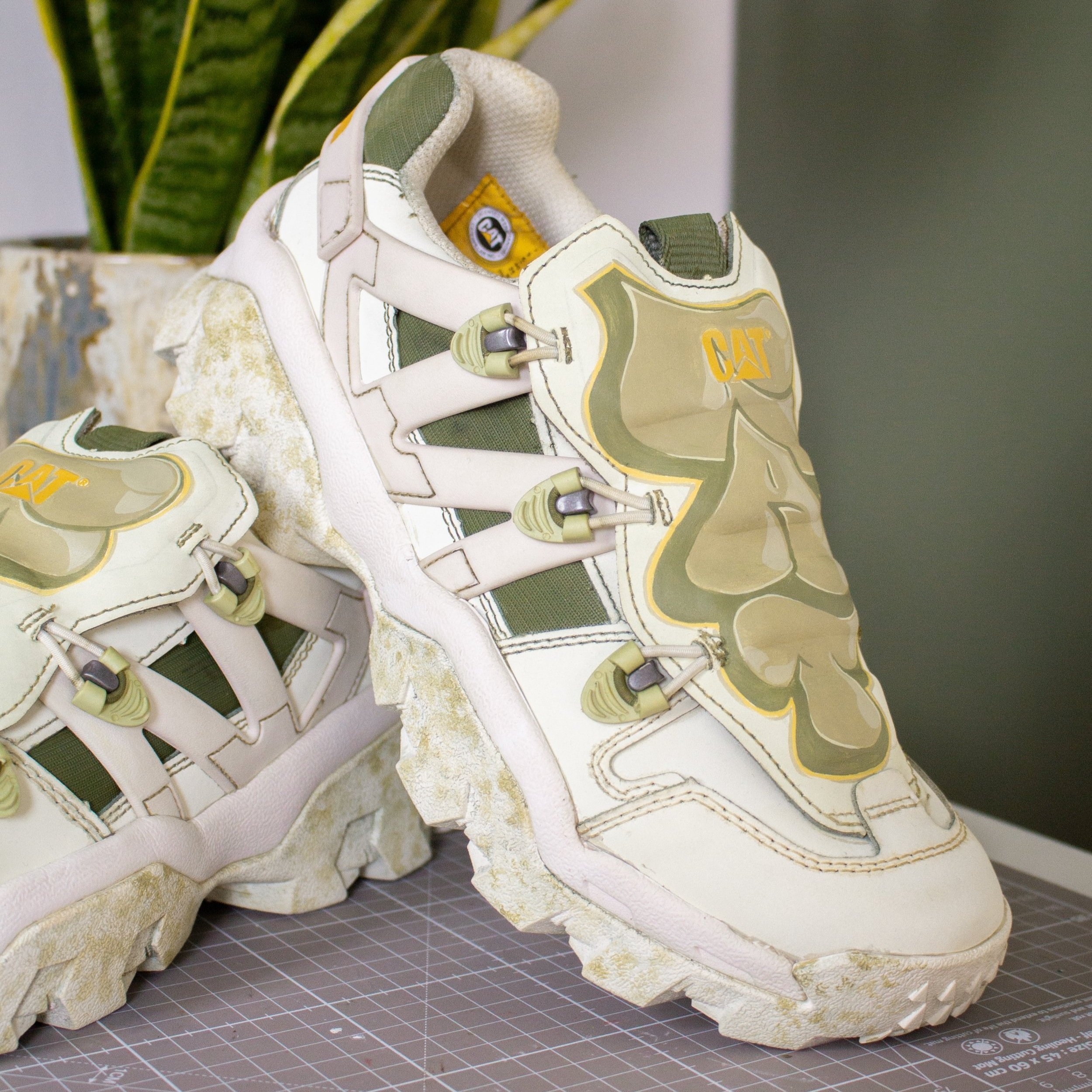 CAT sneakers with bold illustrations in white and green colors.