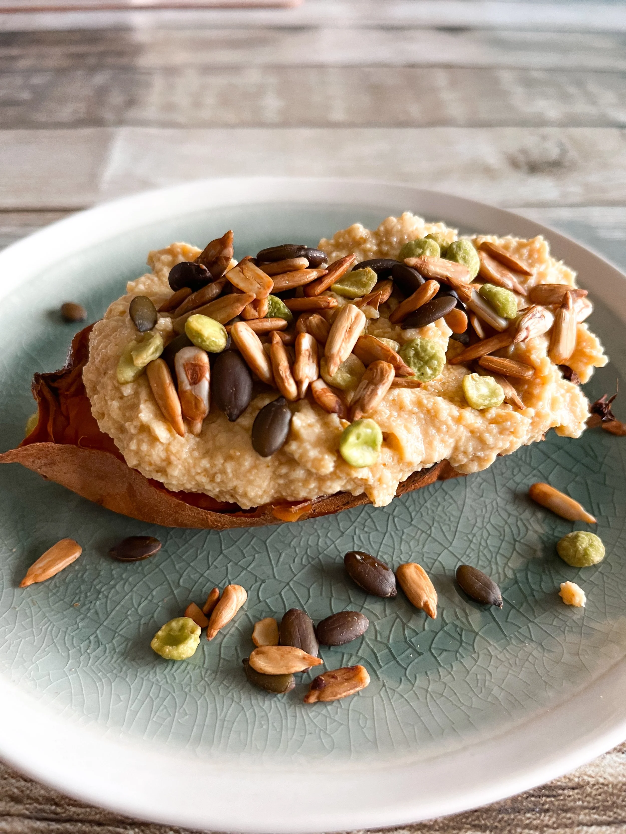 Sweet potato topped with hummus and toasted seeds