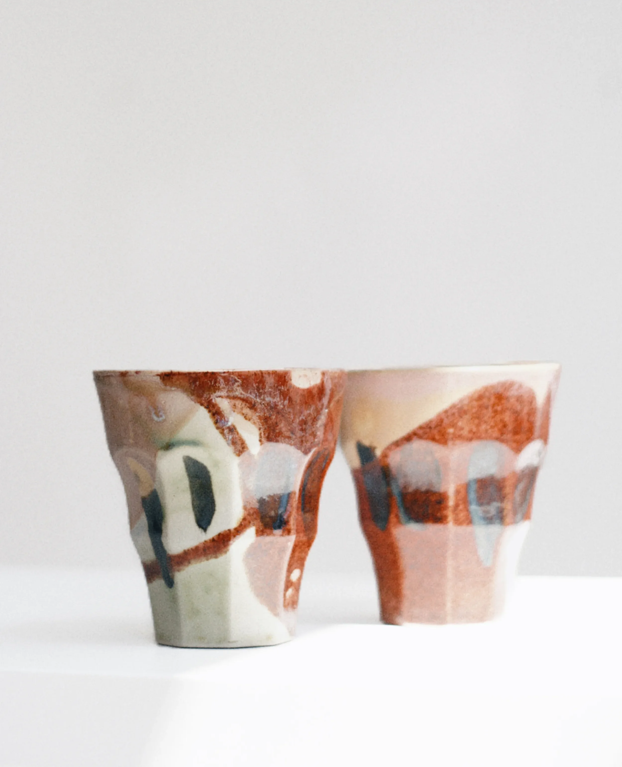 Collection of handmade ceramic cups with abstract painted designs from Marti Ceramic Studio