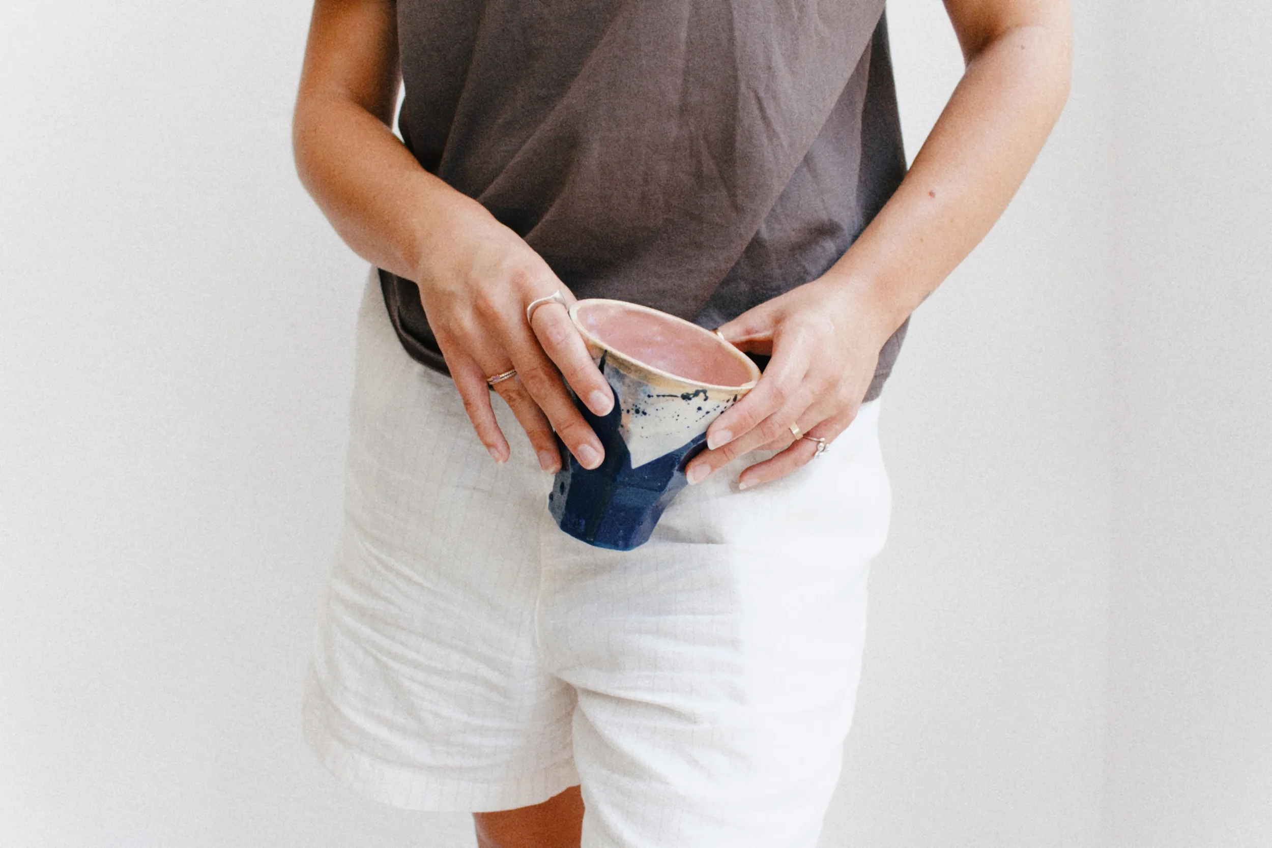 Model holding a handmade blue ceramic bowl in a minimalist lifestyle scene for Marti Ceramic Studio