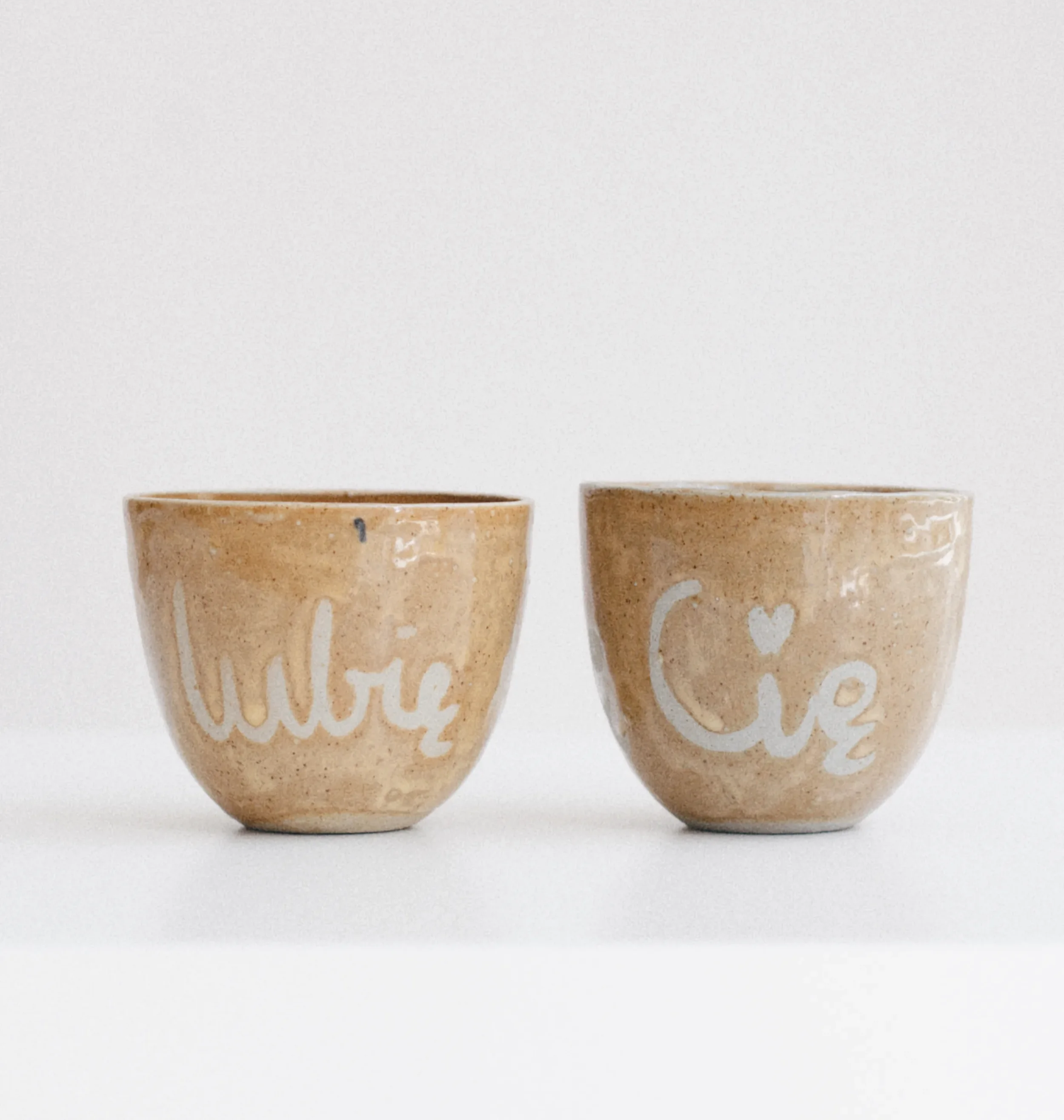 Pair of handmade beige ceramic cups with painted details from Marti Ceramic Studio collection