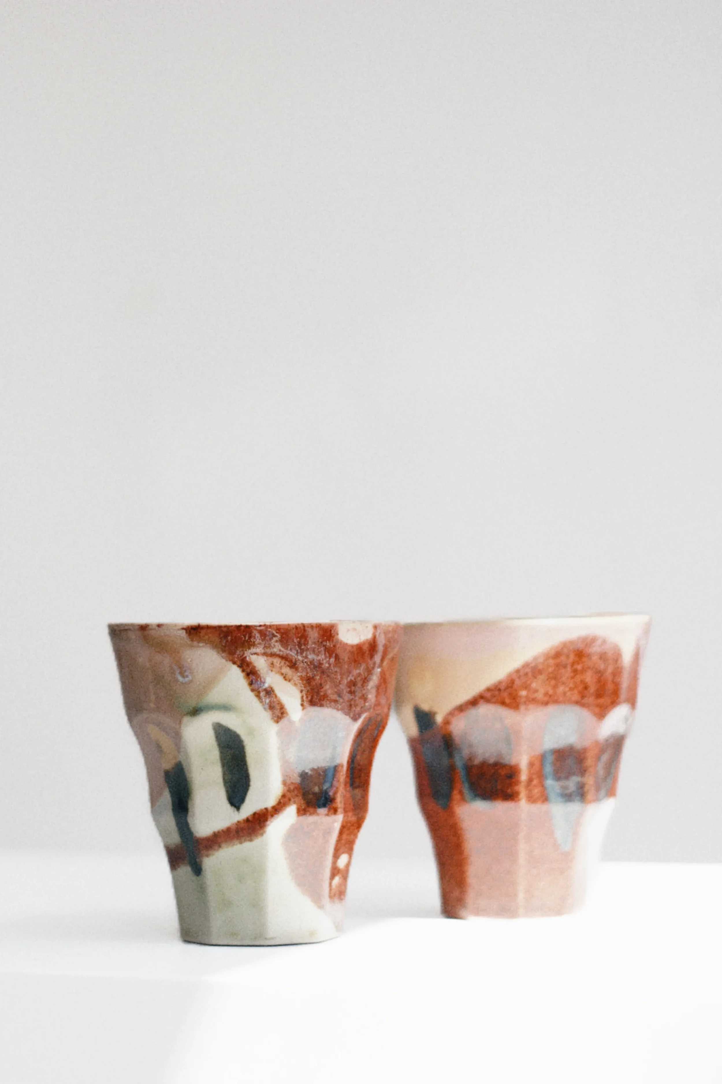 Collection of handmade ceramic cups with abstract painted designs from Marti Ceramic Studio