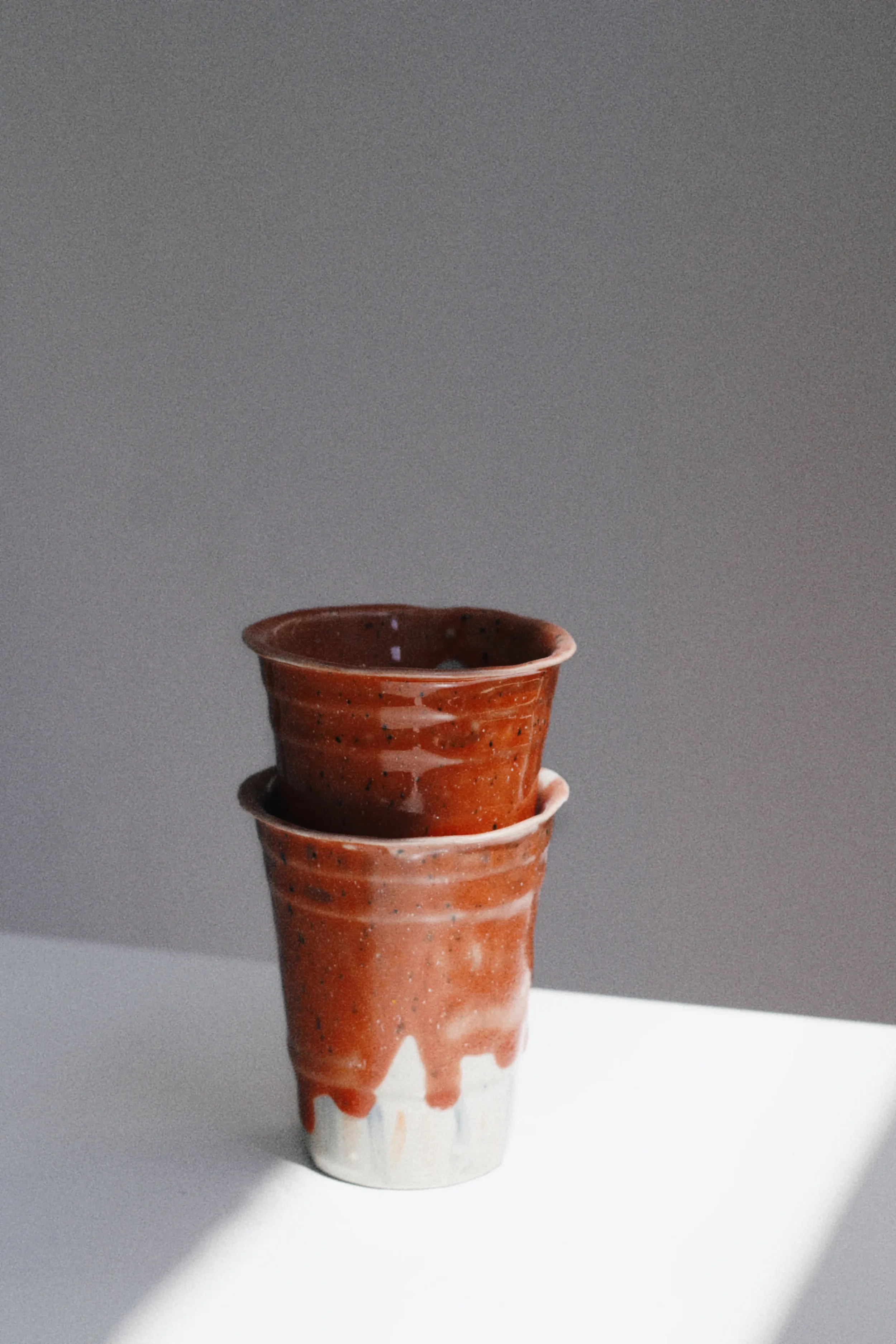Handmade red ceramic cups with textured glaze photographed for Marti Ceramic Studio