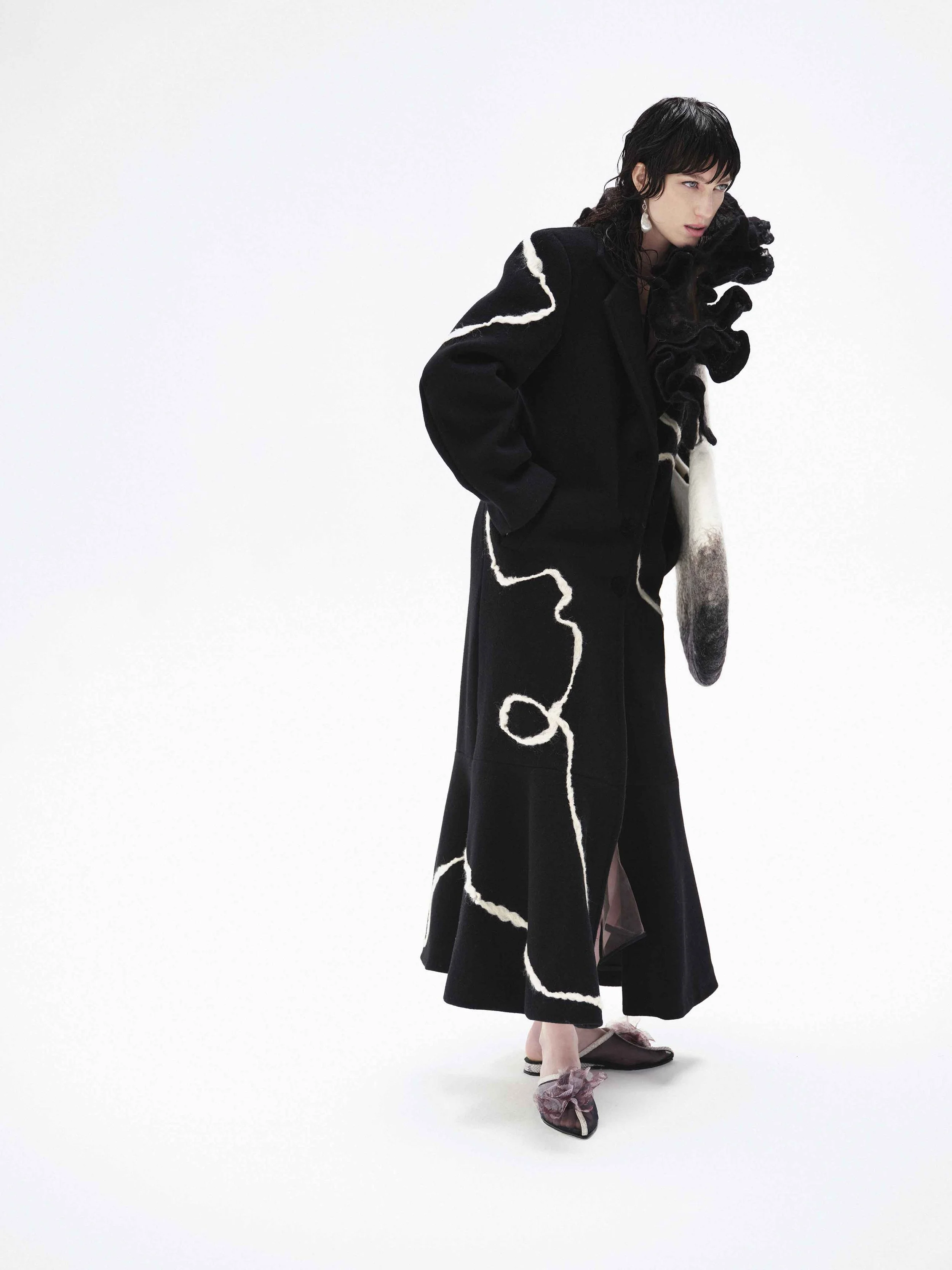 Person wearing a long black coat with white line design