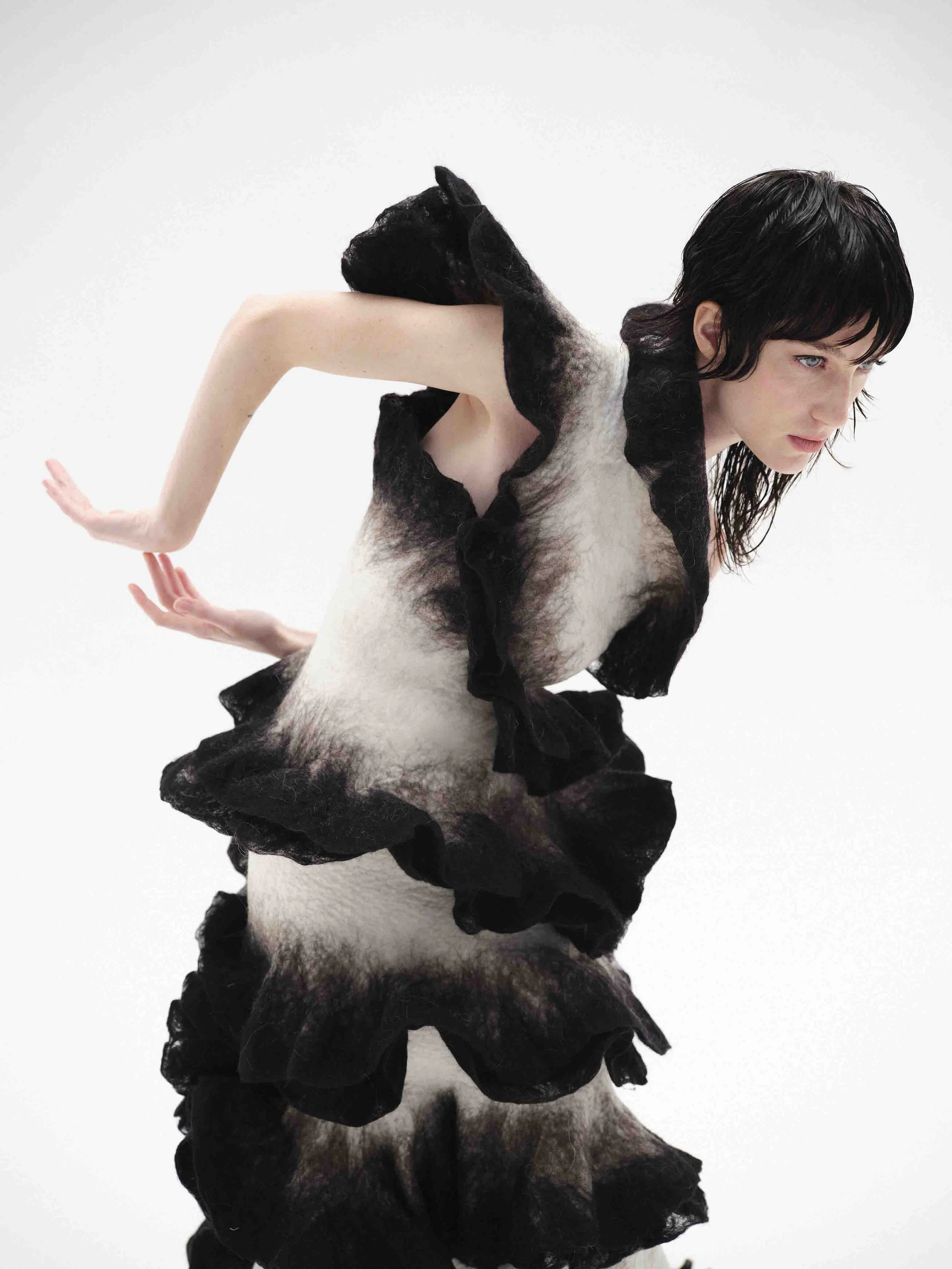 Woman in black and white ruffled dress posing against a white background.