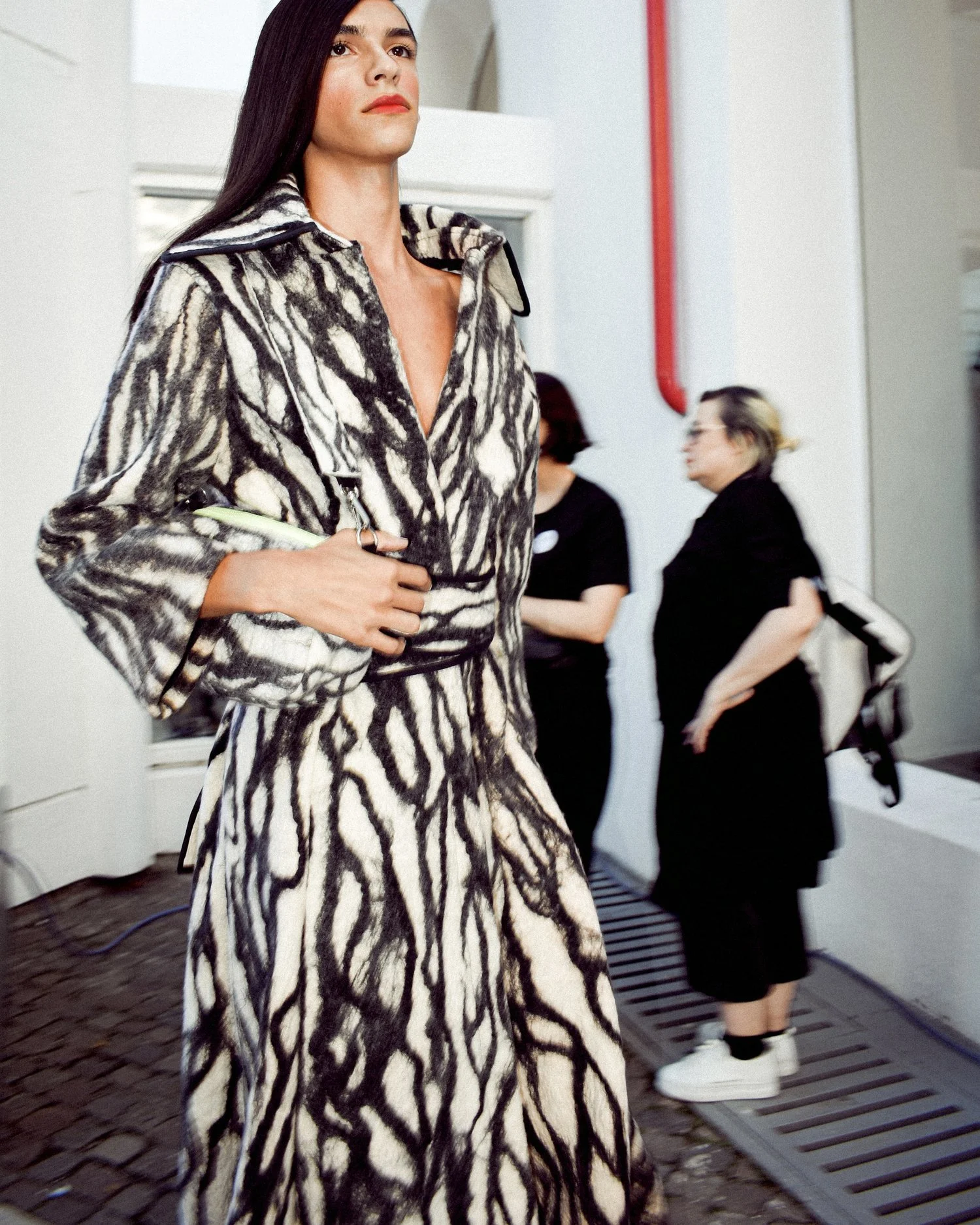 A fashion model wearing a patterned coat on a runway.
