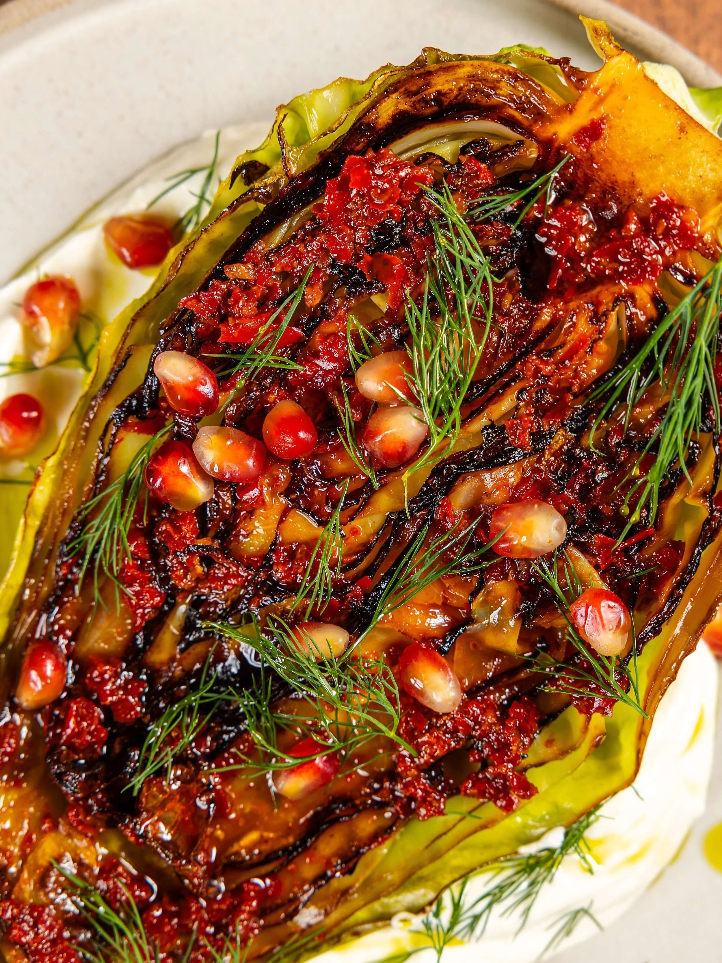 Close-up of a grilled or roasted vegetable with red sauce, garnished with fresh dill and pomegranate seeds