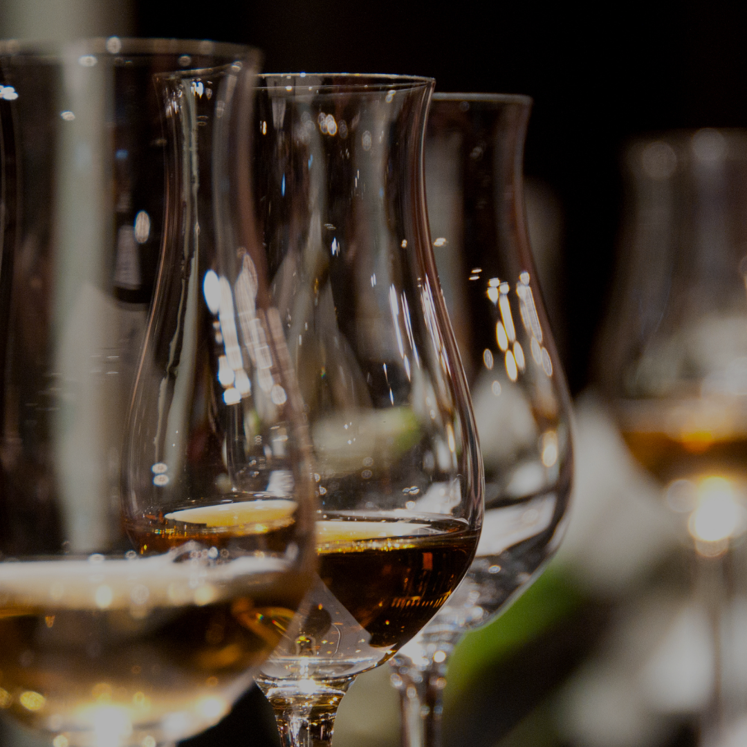 Several wine glasses filled with red wine lined up on a table.