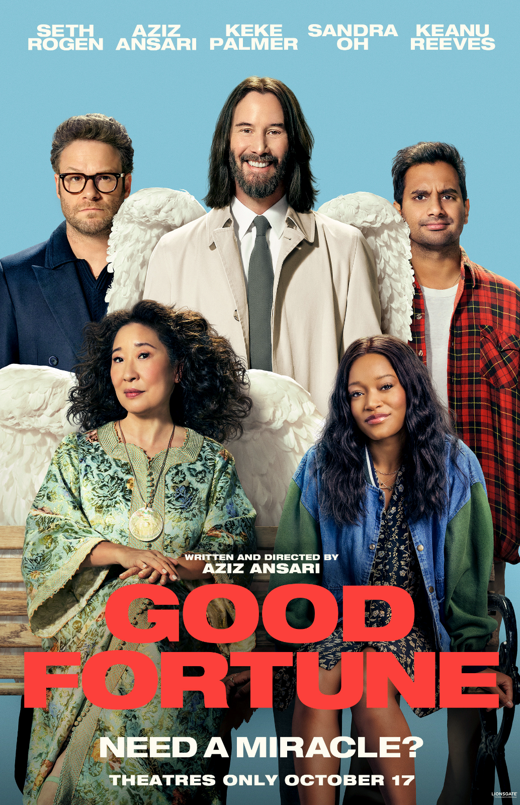The poster features six diverse cast members, including angels with wings, for the movie "Good Fortune." The central figure is a man with long dark hair, a beard, and angel wings, smiling. To his left, a man with glasses and dark hair with wings, and to his right, a man in a red plaid shirt with wings. Two women sit in front; one has curly black hair and is wearing a colorful, traditional-style dress with a large necklace, and the other has long dark hair, wearing a denim jacket over a patterned outfit. The background is blue, and the movie title is in bold red and white text at the bottom, with the tagline "Need a miracle?" and release date "Theatres only October 17."